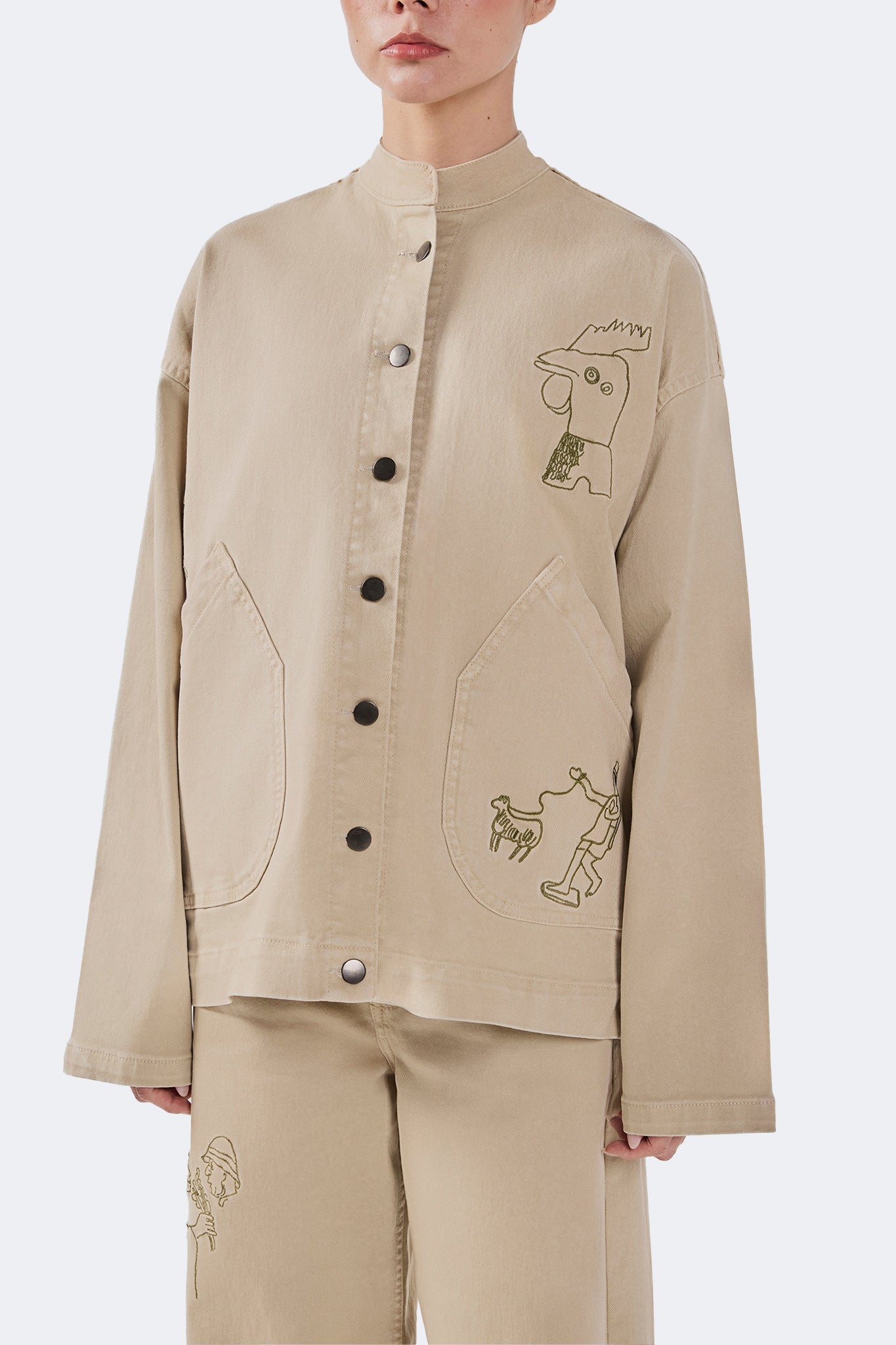 Side detail of the Allpa Mandarin Jacket in Cream showcasing embroidered artwork, oversized pocket construction, and clean tailoring.