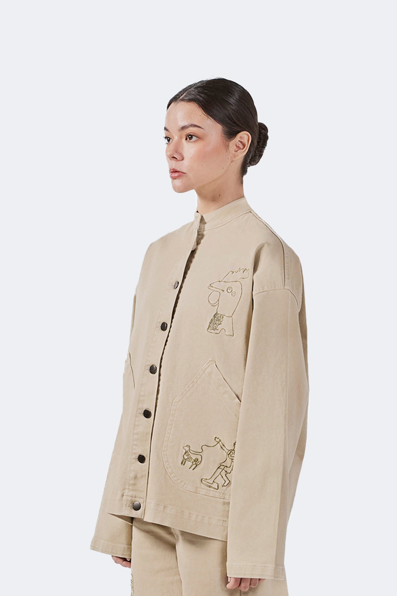 Side detail of the Allpa Mandarin Jacket in Cream showcasing embroidered artwork, oversized pocket construction, and clean tailoring.