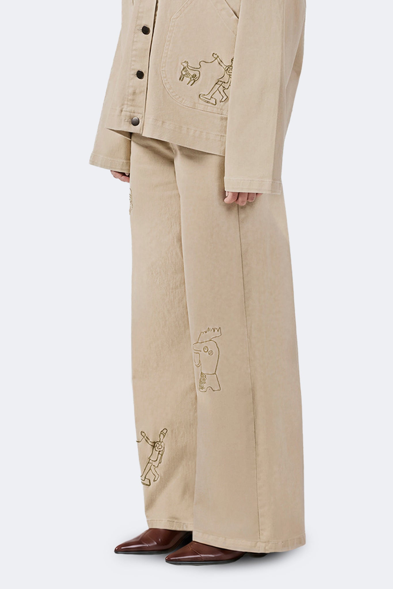 Side detail of the Allpa Cream cotton denim jeans showcasing embroidered archive motifs.