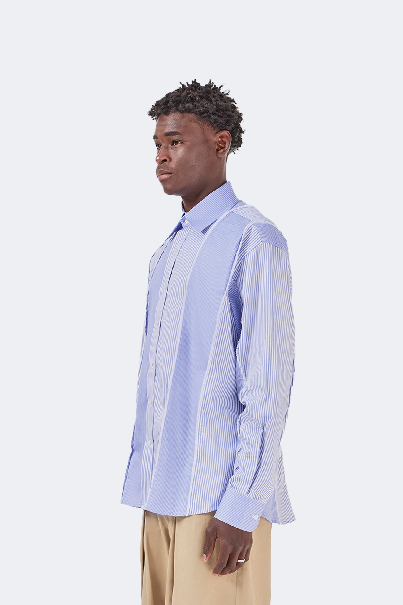 Side detail of the Canoa Blue Striped Shirt highlighting the relaxed fit, exposed raw-edge seams, and striped fabric.