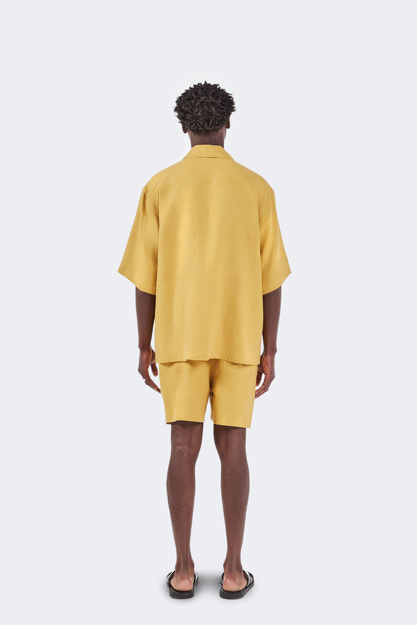 Back view of the Floreana Short-Sleeved Shirt in Mustard crafted from breathable 100% linen with a relaxed silhouette and clean, minimalist design.