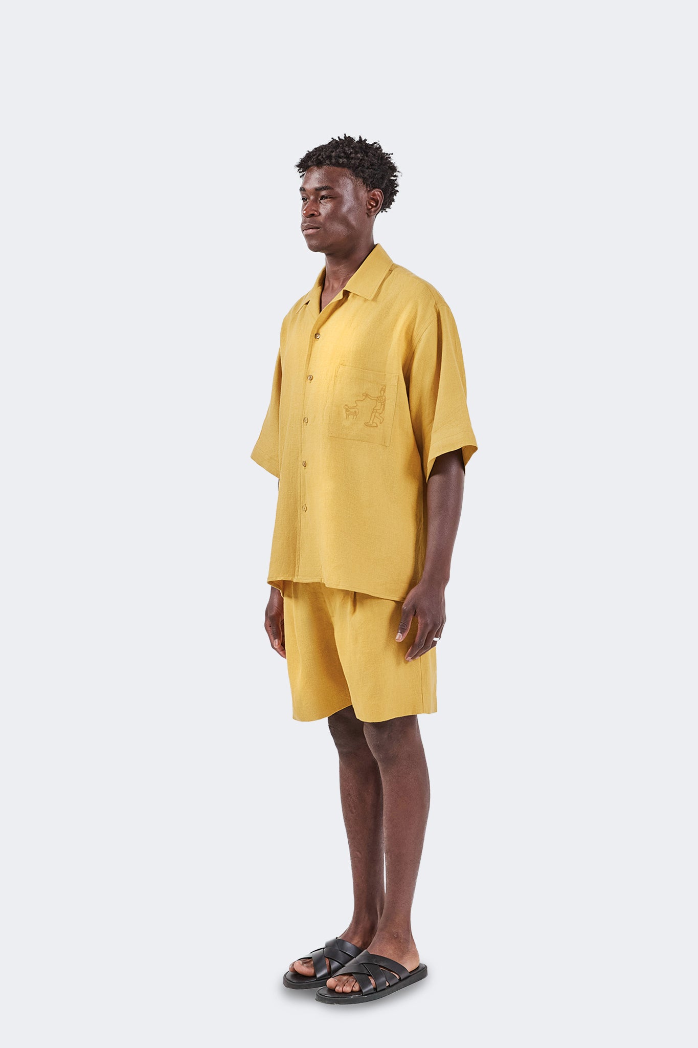 Side view of the Floreana Short-Sleeved Shirt in Mustard showcasing its relaxed silhouette, breathable 100% linen fabric, and effortless drape.