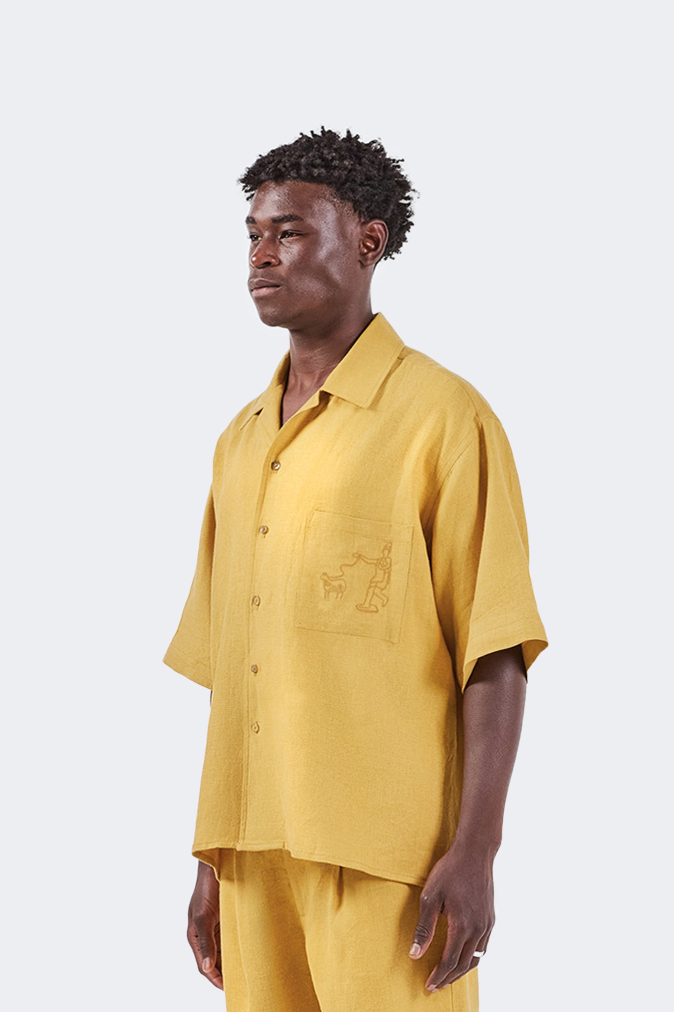 Close-up side view of the Floreana Short-Sleeved Shirt in Mustard highlighting the open collar, relaxed sleeve, and natural linen texture.