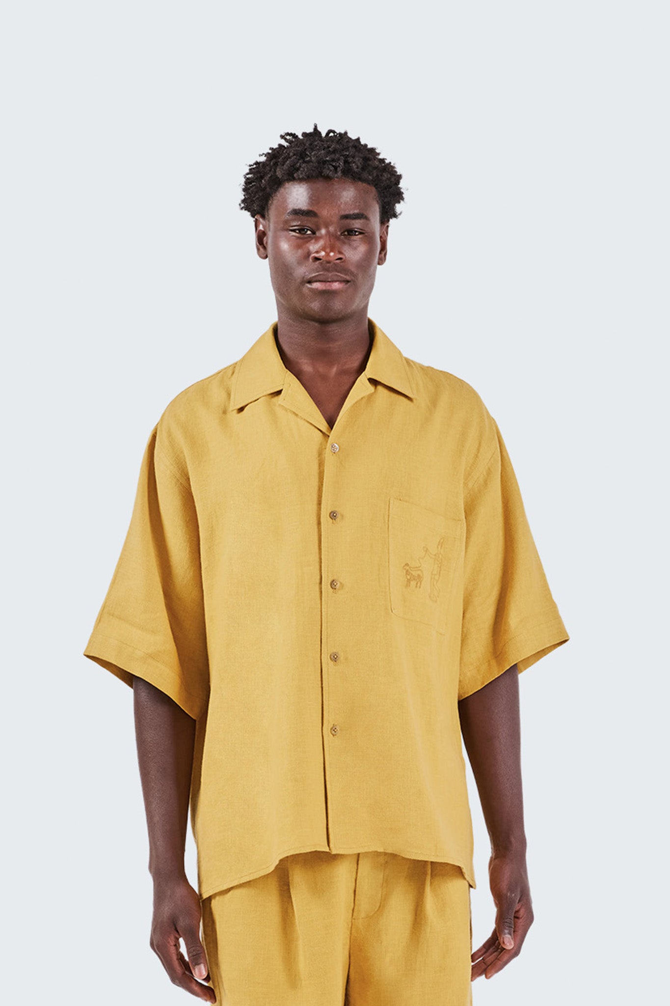 Man wearing a mustard yellow shirt and pants on a white background