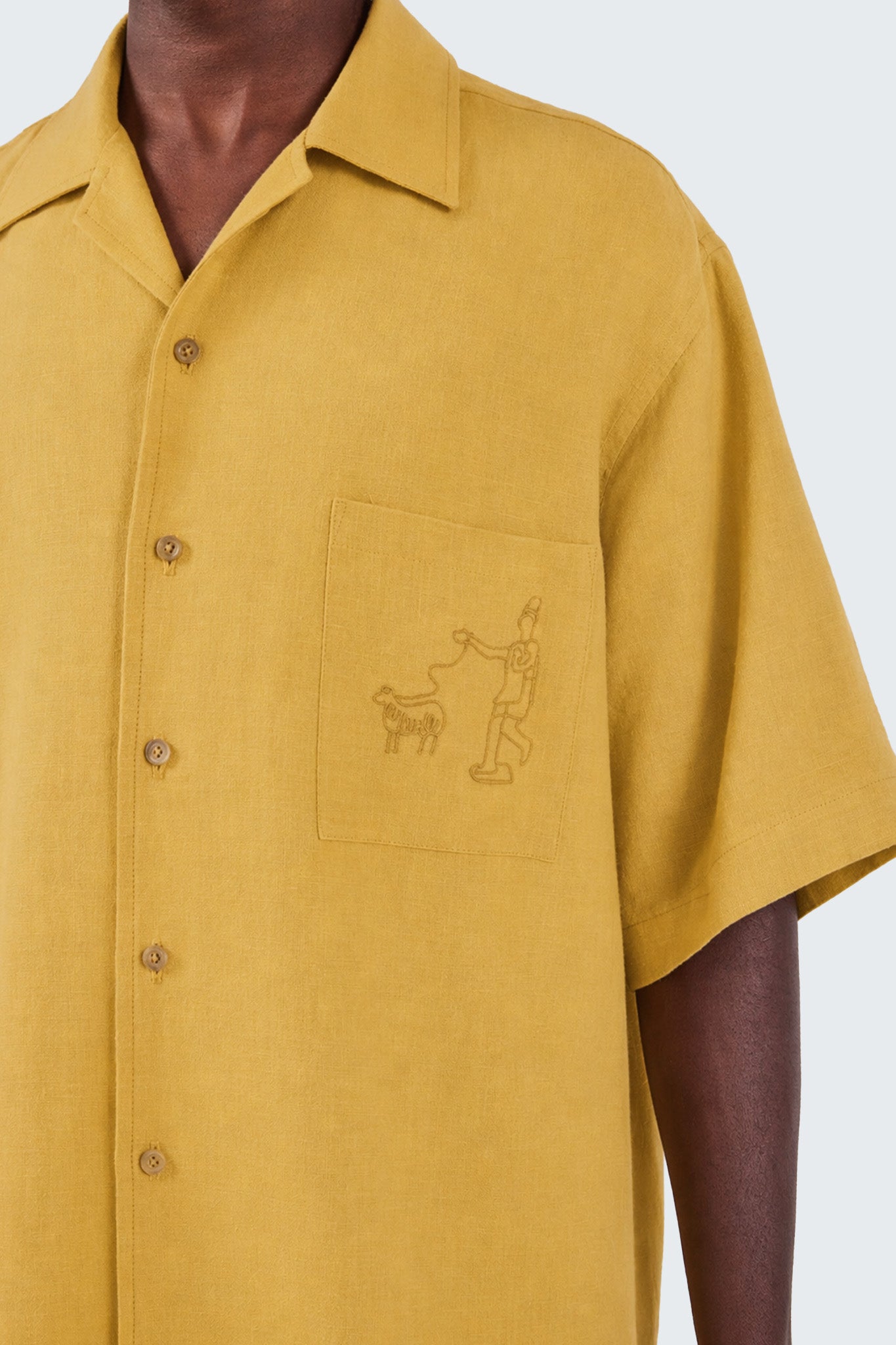 Yellow shirt with a small design on the chest against a white background