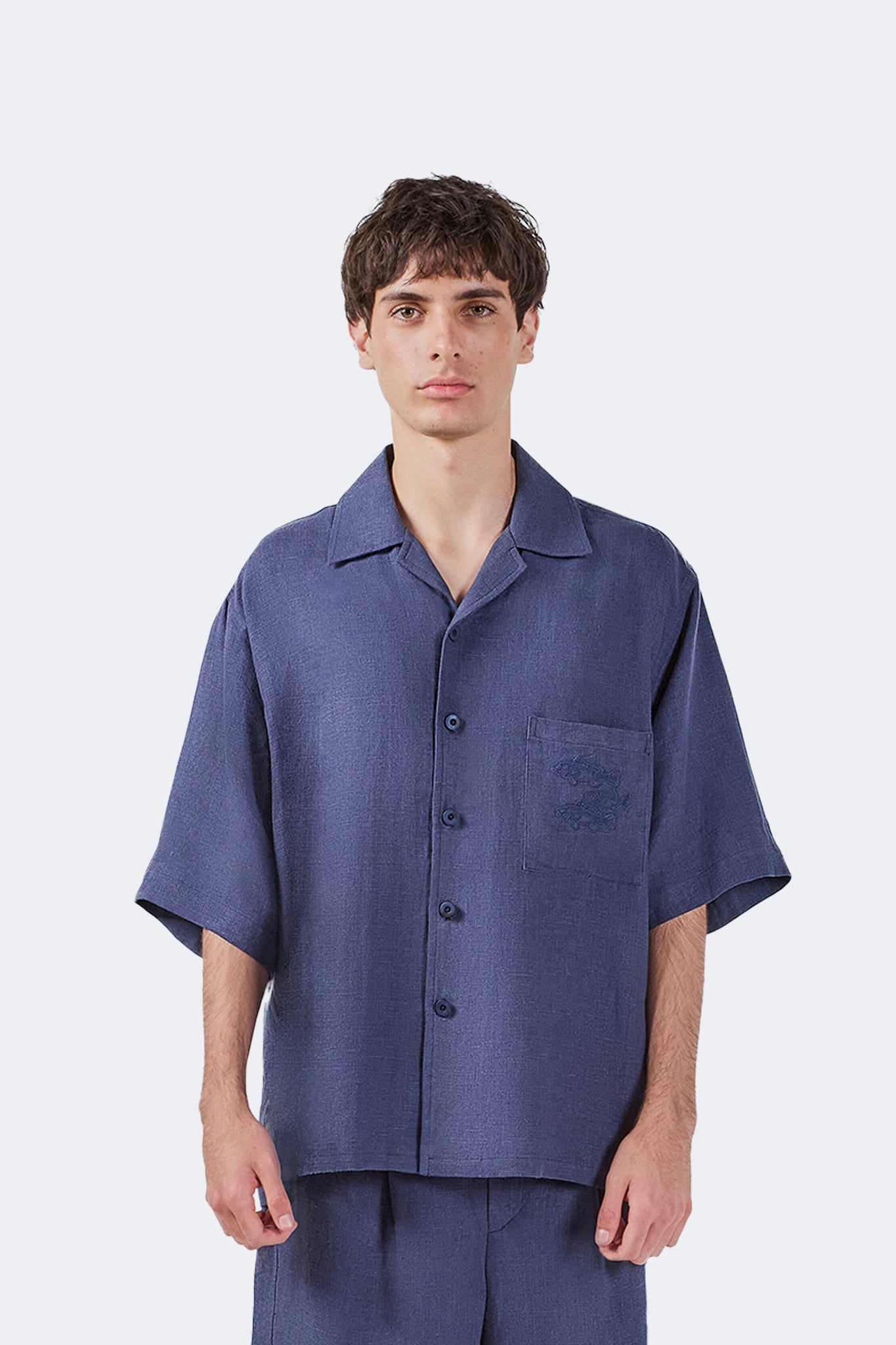 Front view of the Isabela Blue Linen Short-Sleeved Shirt with open camp collar and embroidered chest pocket.