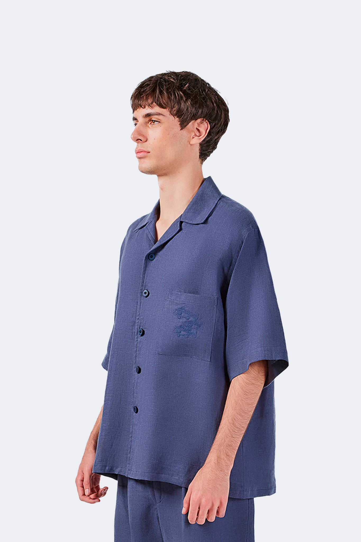 Side profile of the Isabela Blue Linen Short-Sleeved Shirt highlighting the relaxed silhouette and natural linen drape.