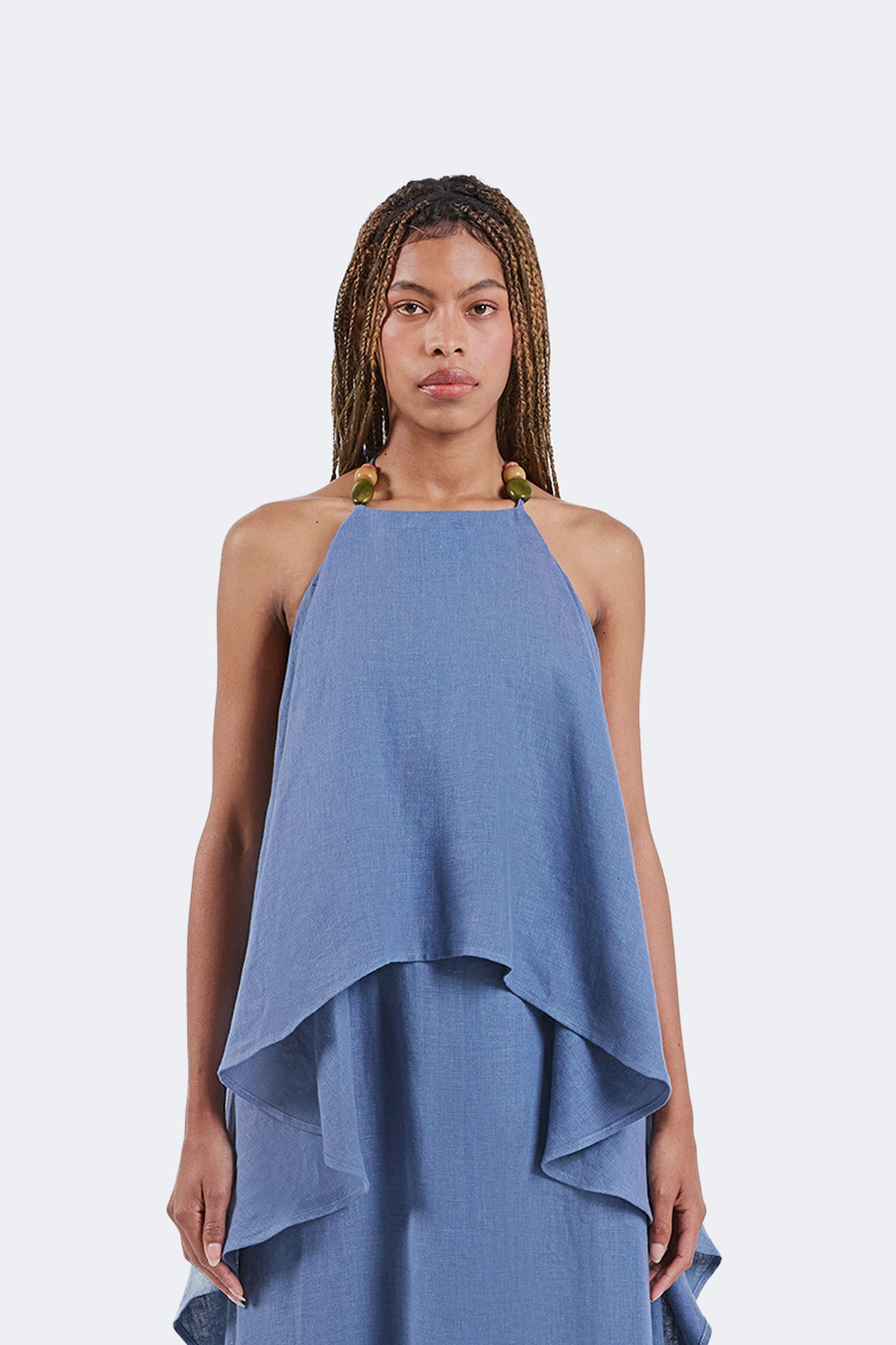 Front detail of the Jama Halter Dress showcasing the halter neckline with handcrafted bead accents, layered draped overlay, and lightweight Sky blue linen.