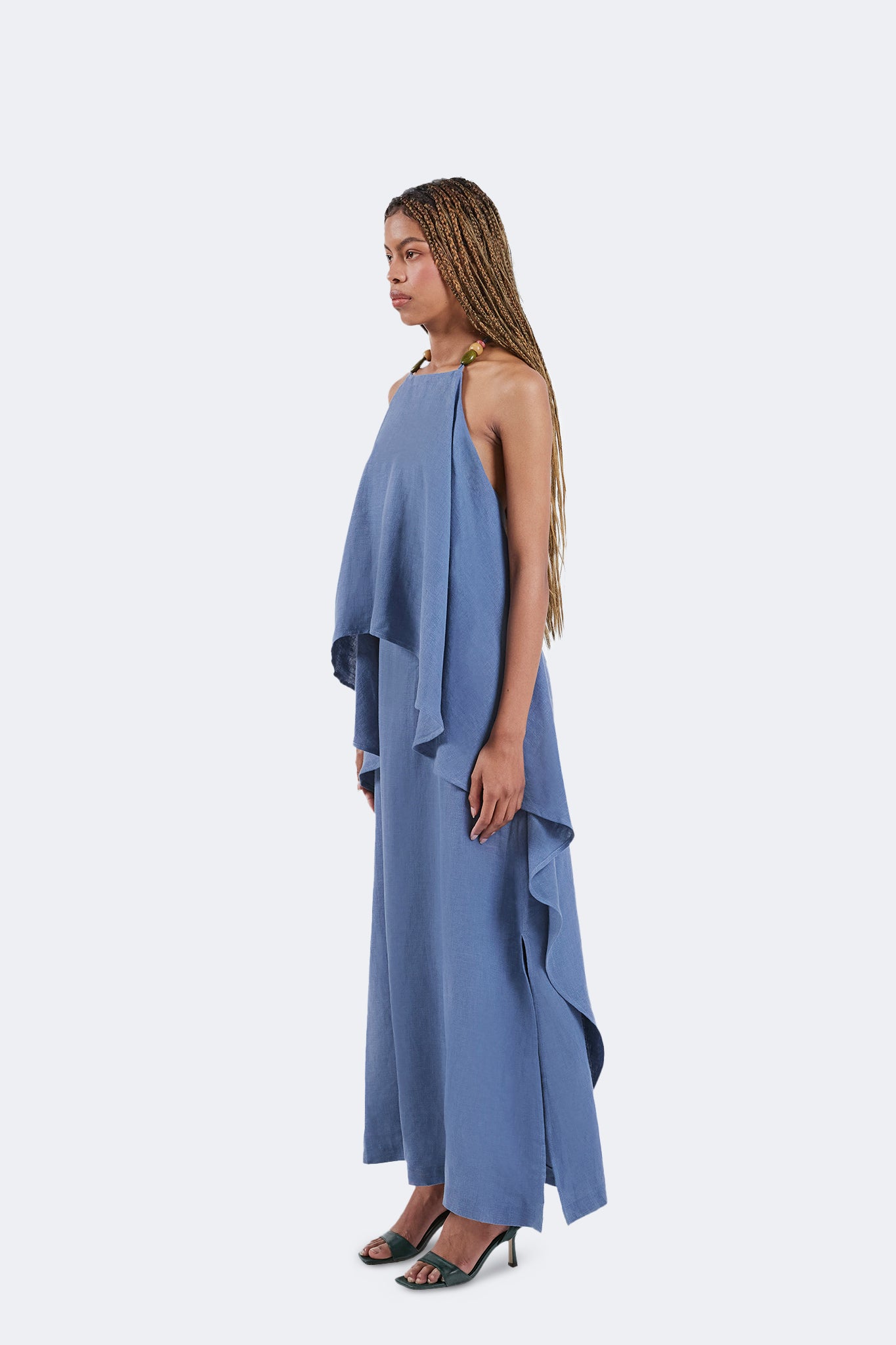 Side view of the Jama Halter Dress showcasing the cascading layered construction, lightweight linen fabric, and elegant full-length silhouette.