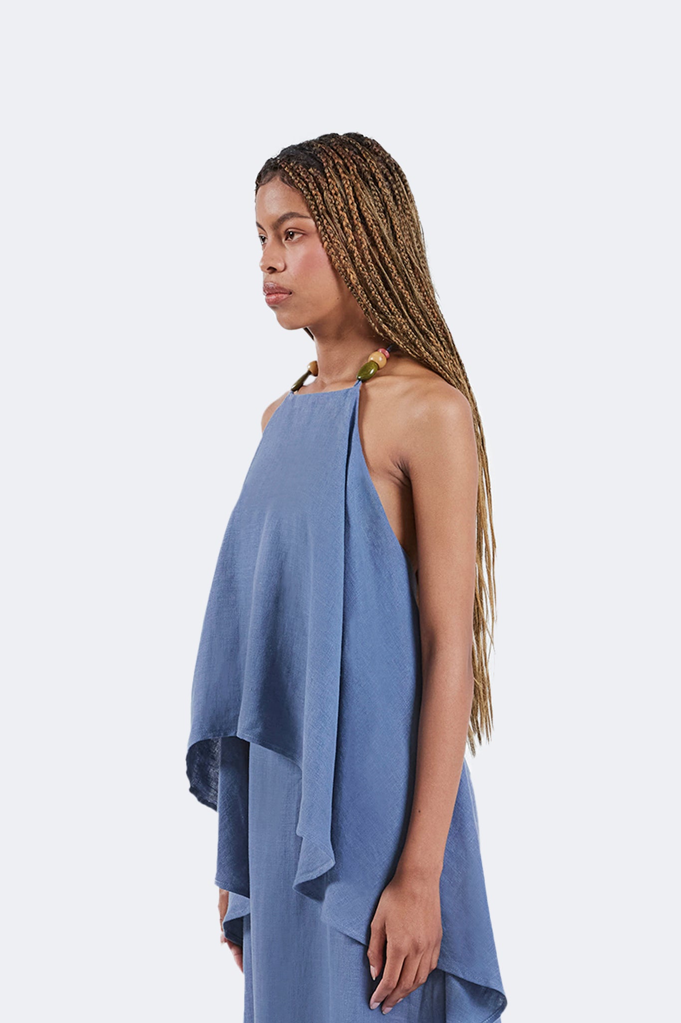Side detail of the Jama Halter Dress in Sky blue linen featuring a flowing layered silhouette, handcrafted bead halter neckline, and lightweight draped construction.