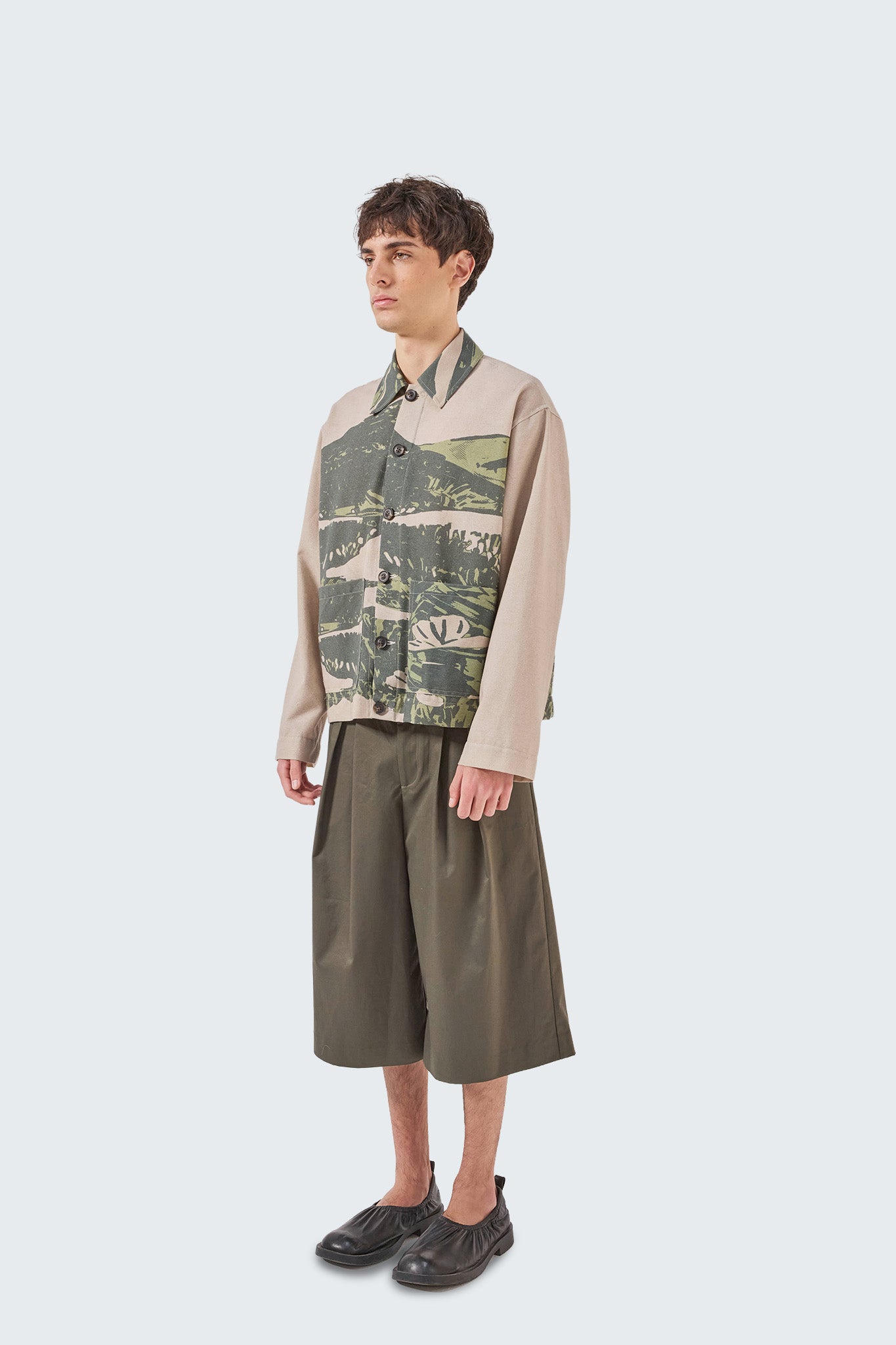 Kikuyo Workman Jacket in moss and beige landscape print, side view showing relaxed linen workwear silhouette and patch pockets.
