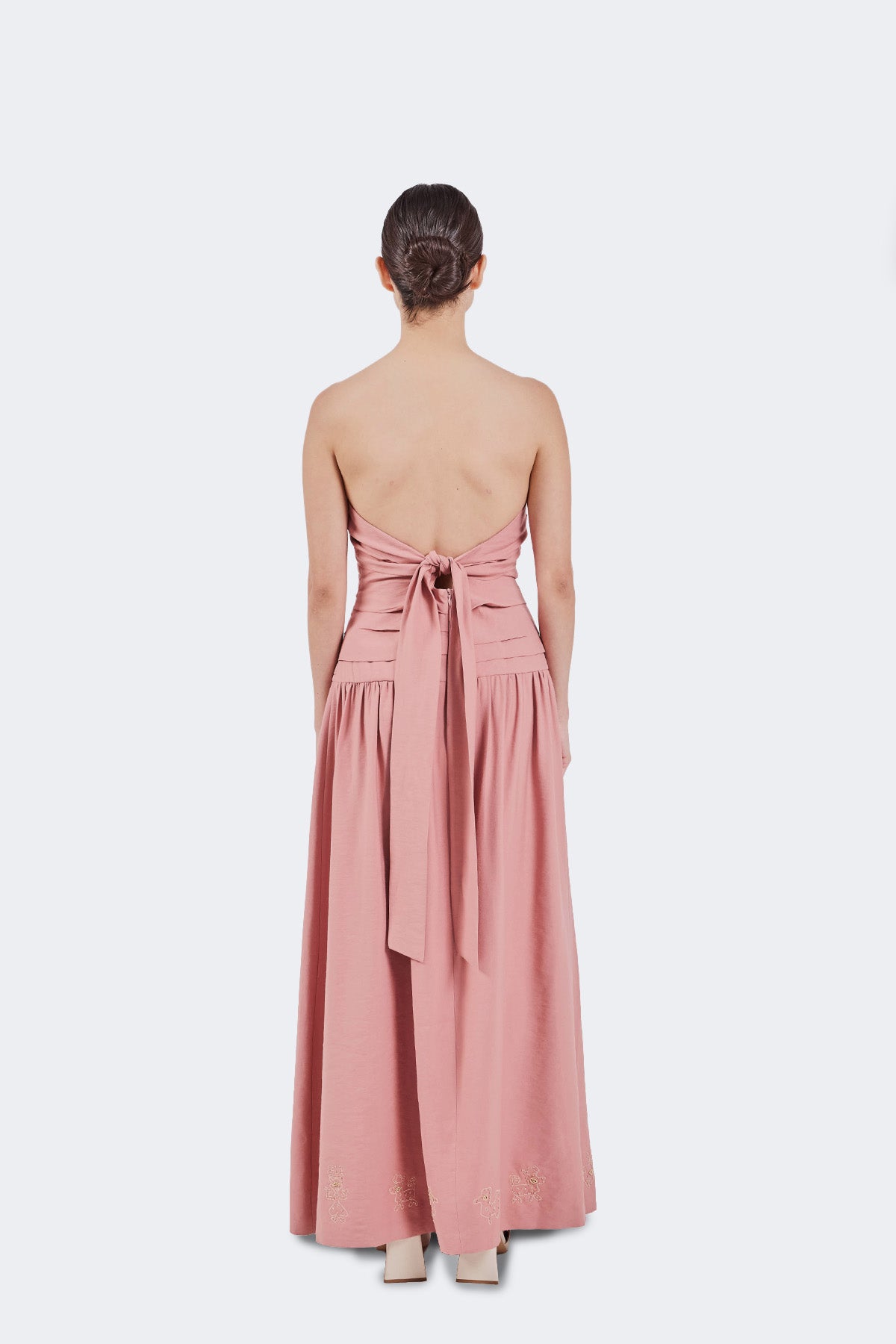 Pink strapless dress with a tie waist on a white background