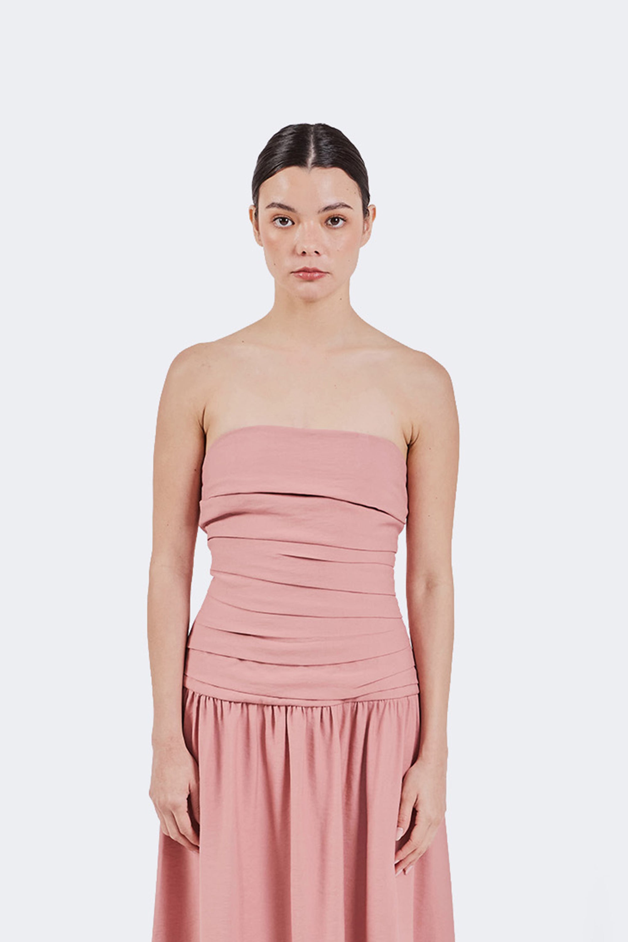 Woman wearing a pink strapless dress against a white background