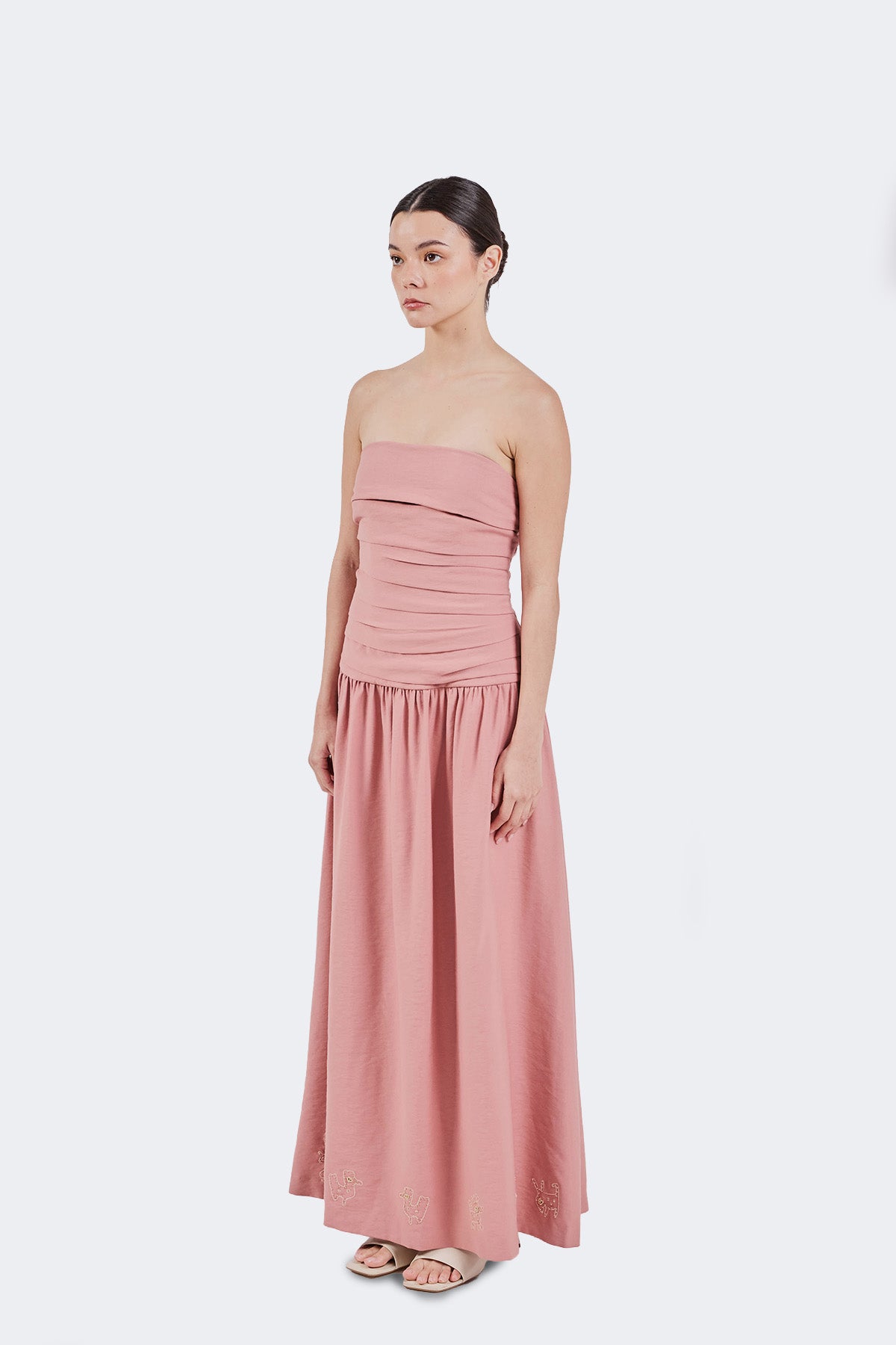 Woman wearing a pink strapless dress on a white background