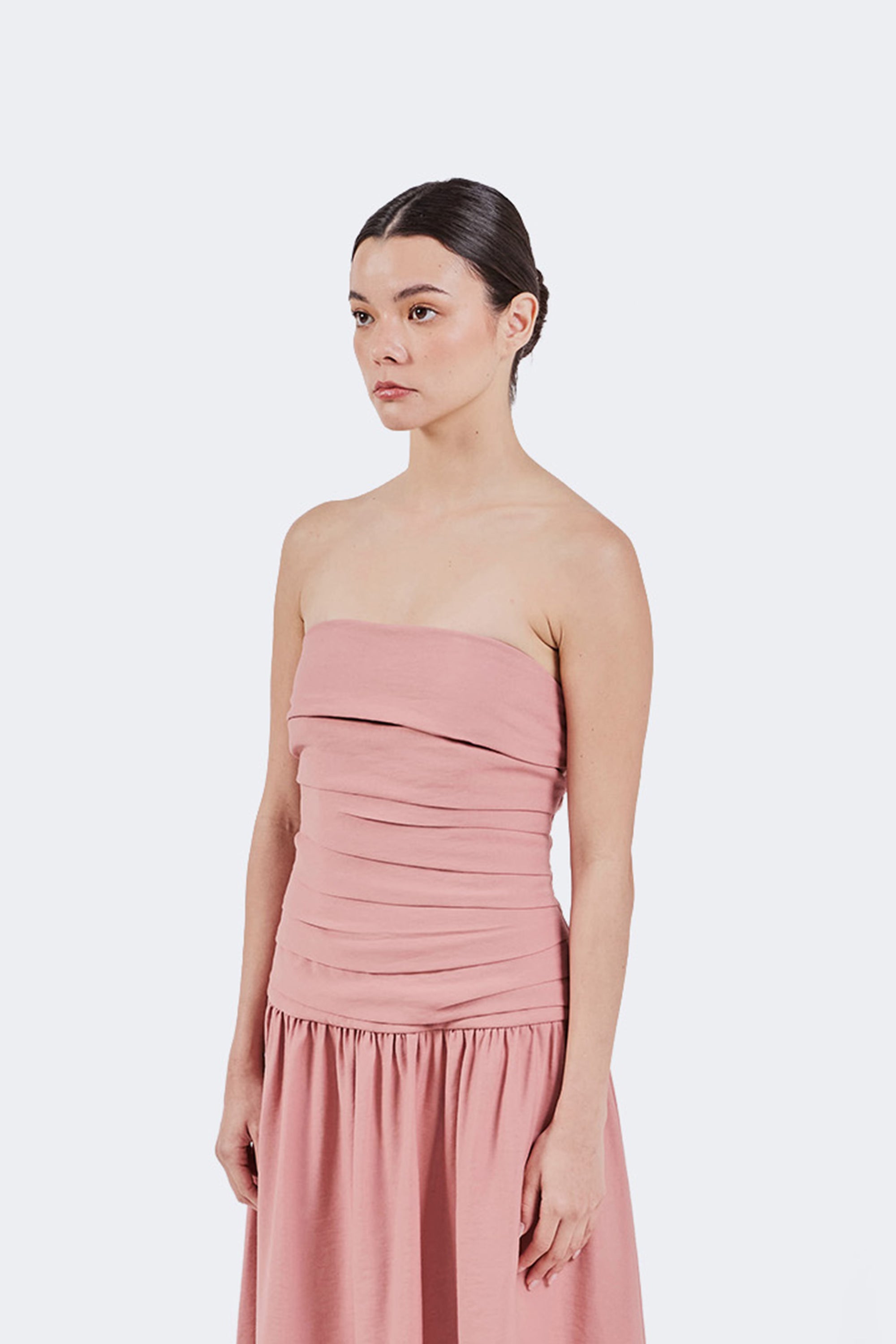 Woman wearing a pink strapless dress against a white background