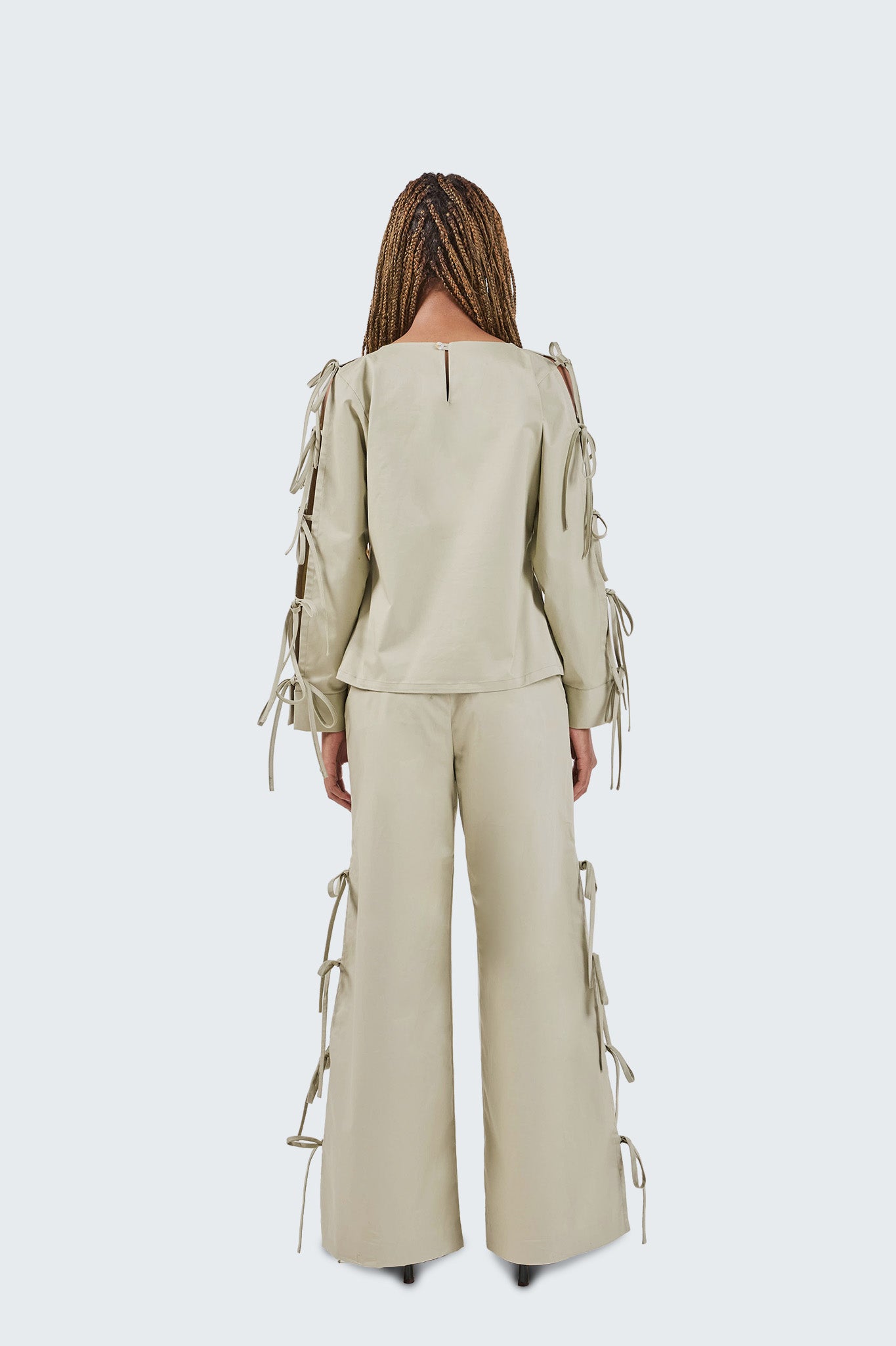 Woman wearing a beige outfit with lace-up details on a white background