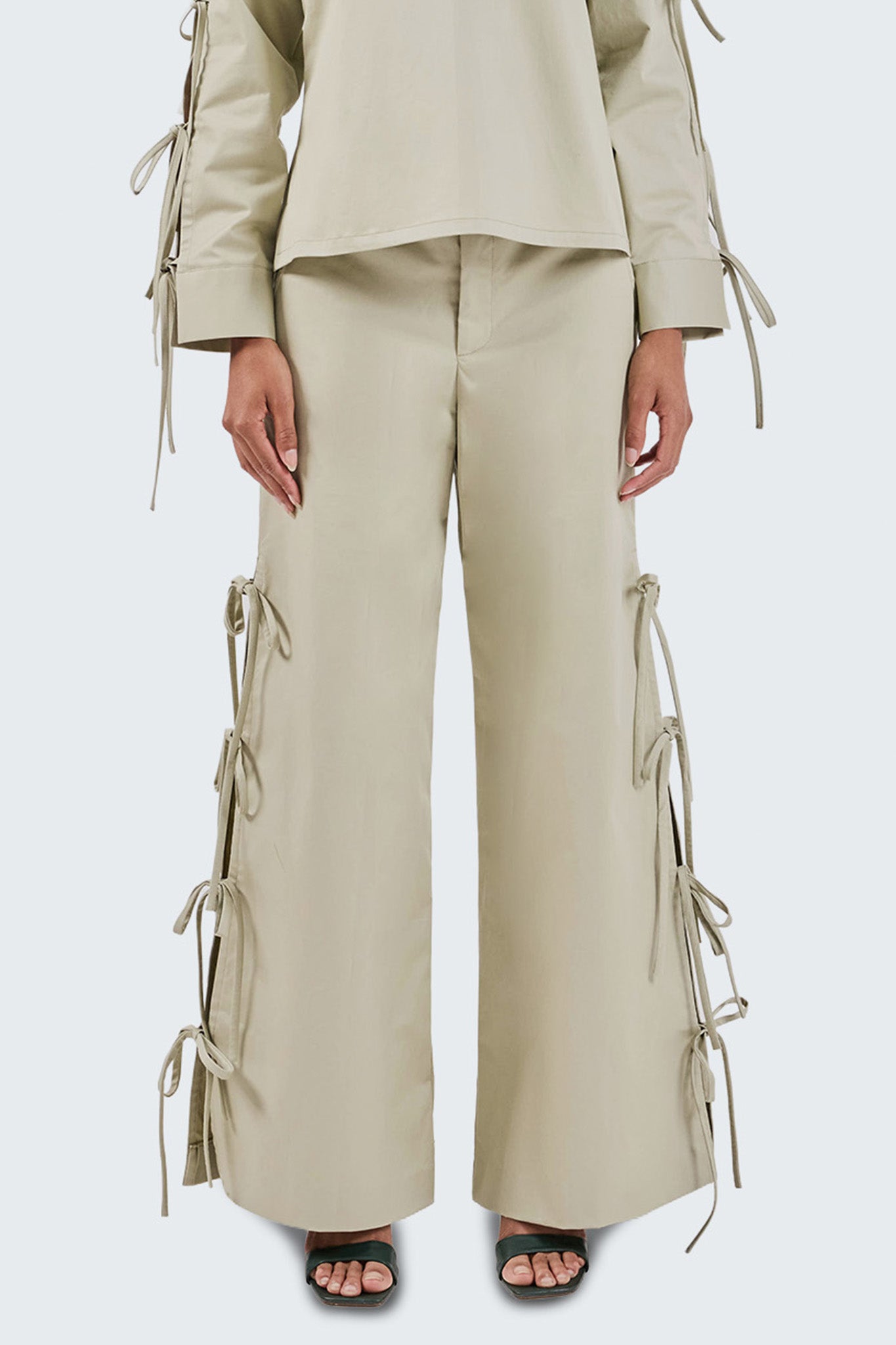 Beige outfit with wide-leg pants and lace-up details on a white background