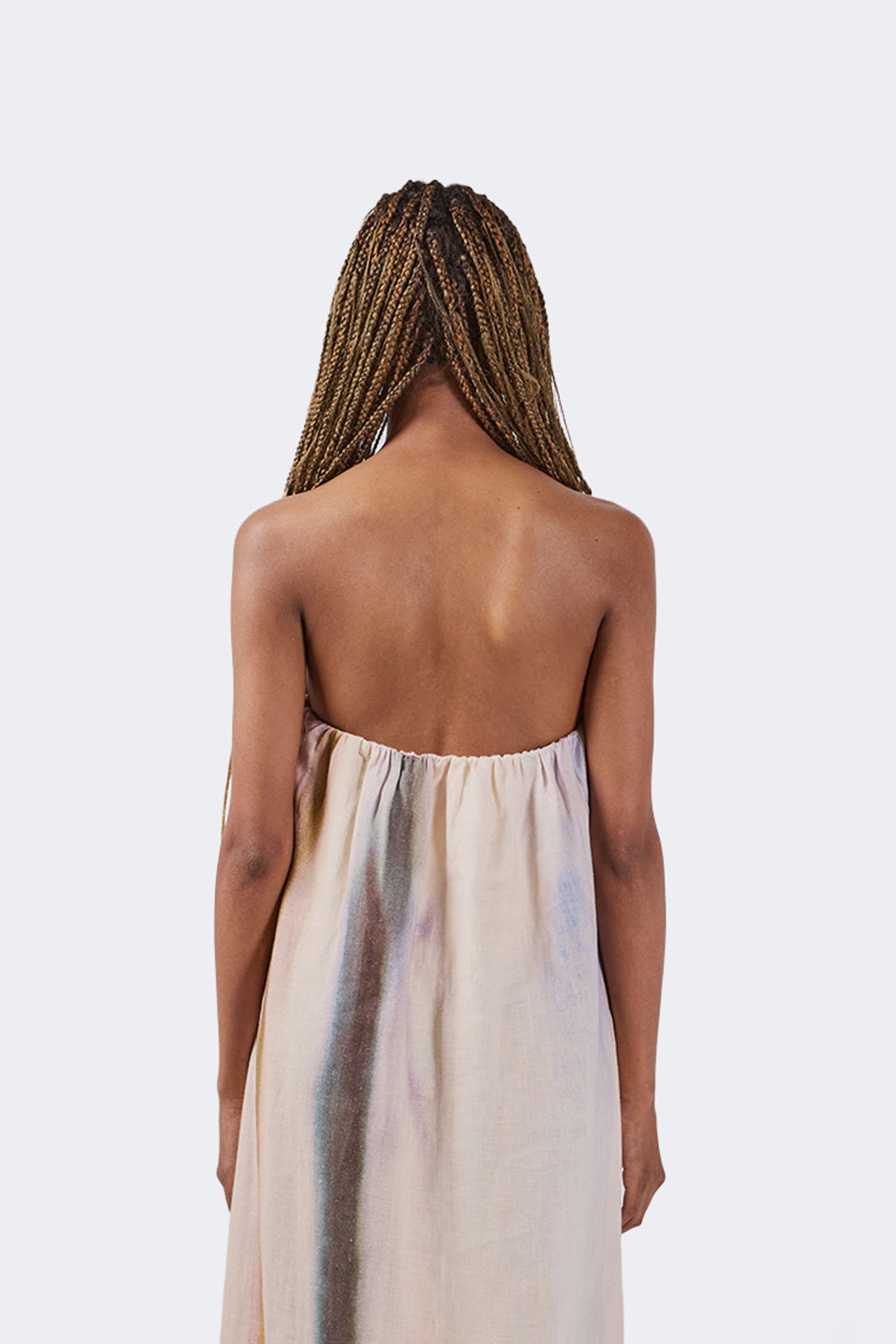 Woman wearing a strapless beige dress with braided hair on a white background