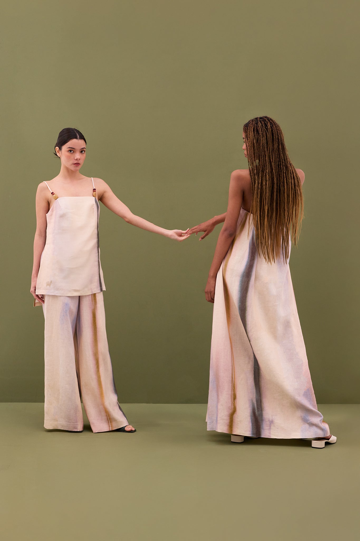 Model wearing the Ópalo Strapless Dress in lightweight linen, shown from the back. The full-length silhouette features soft mineral-inspired tonal gradients and a fluid drape that highlights the dress’s elegant movement and sculptural simplicity.
