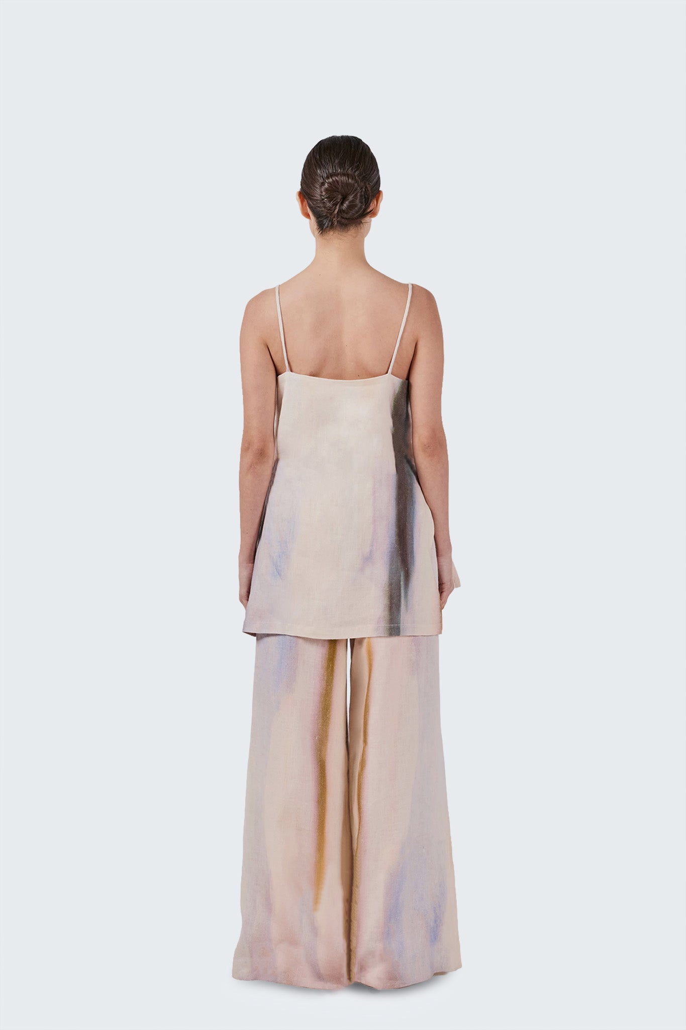 Woman wearing a beige set with a subtle pattern on a white background