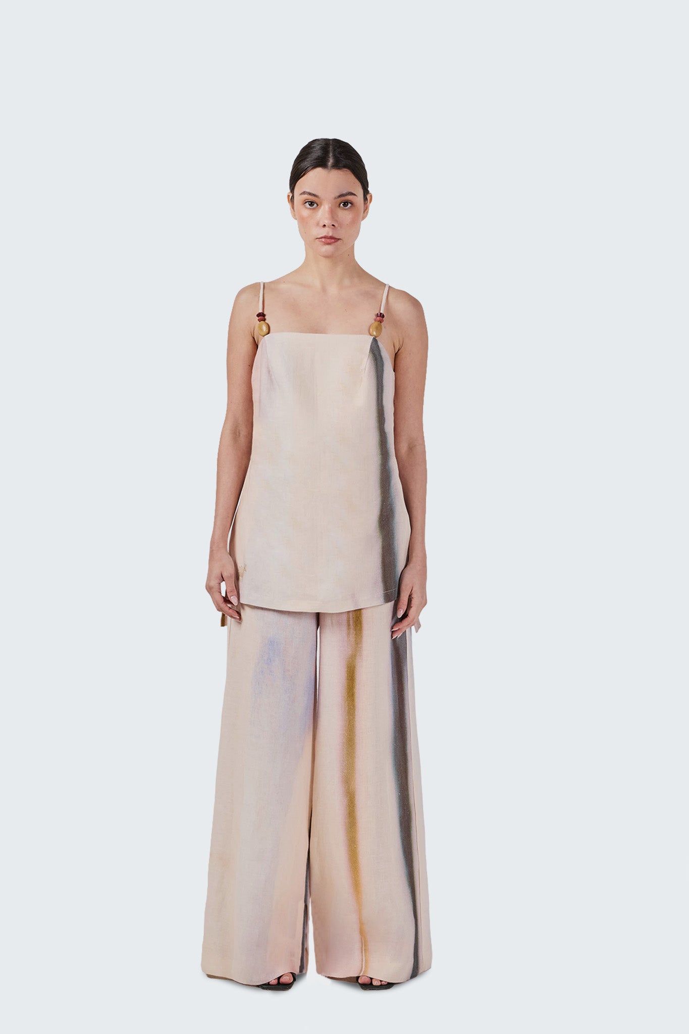 Woman wearing a beige dress with sheer overlay on a white background