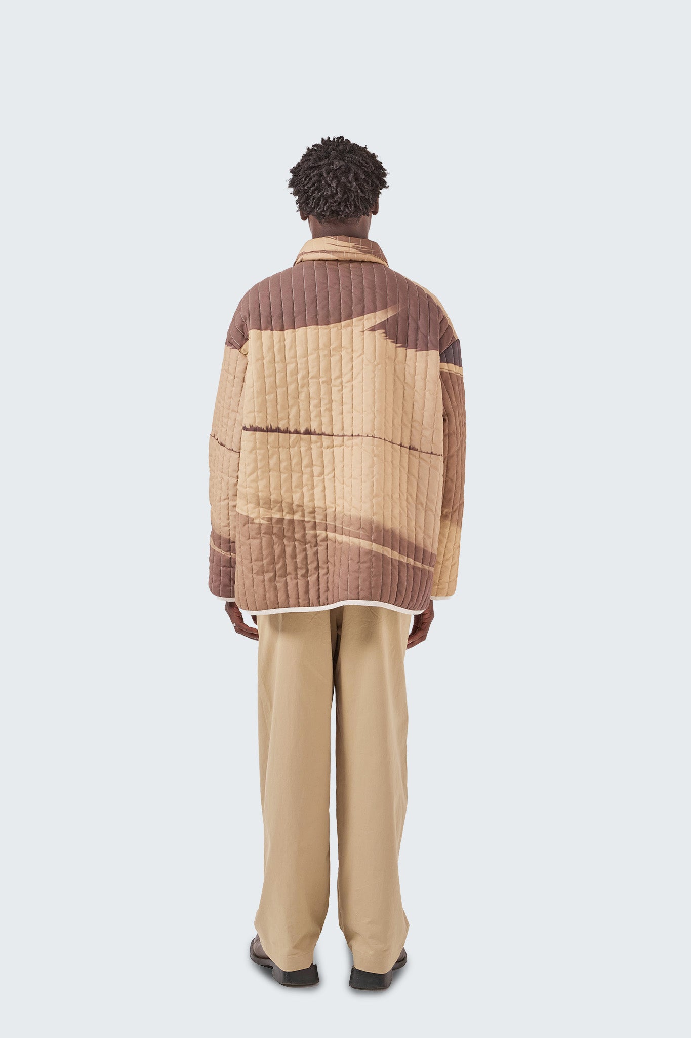 Back view of the Palmira Quilted Jacket featuring continuous Palmira artwork and vertical quilted stitching.