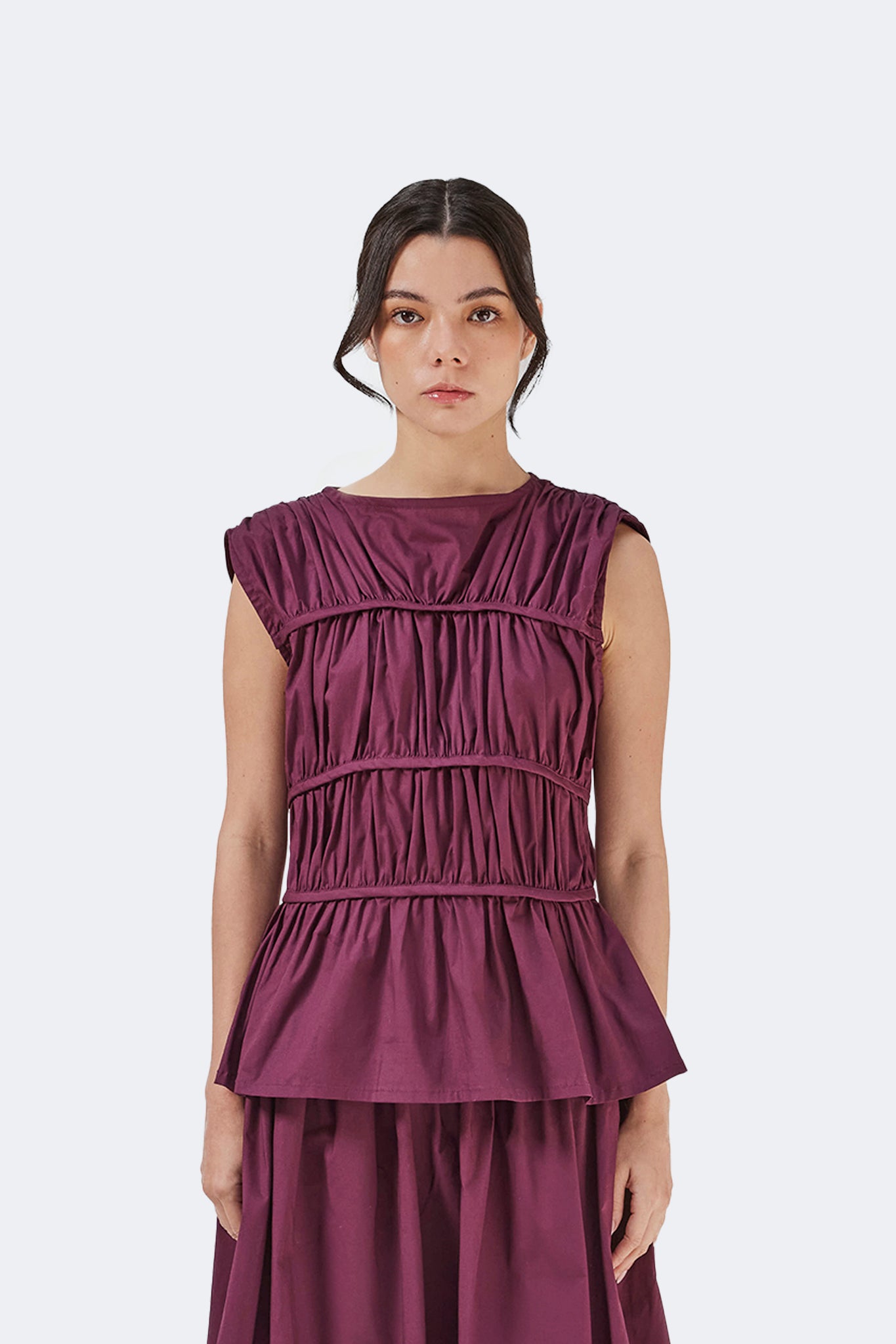 Front detail of the Palo Santo Gathered Blouse in Grape crafted from a cotton blend with sculptural gathered bodice, bateau neckline, and peplum silhouette.