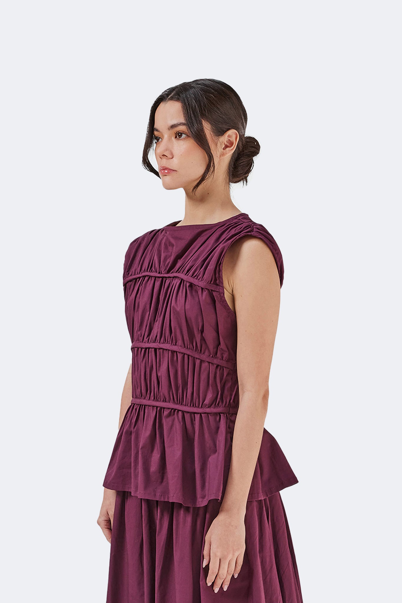 Side detail of the Palo Santo Gathered Blouse in Grape showcasing the sculptural gathered construction, soft structured fit, and peplum hem.