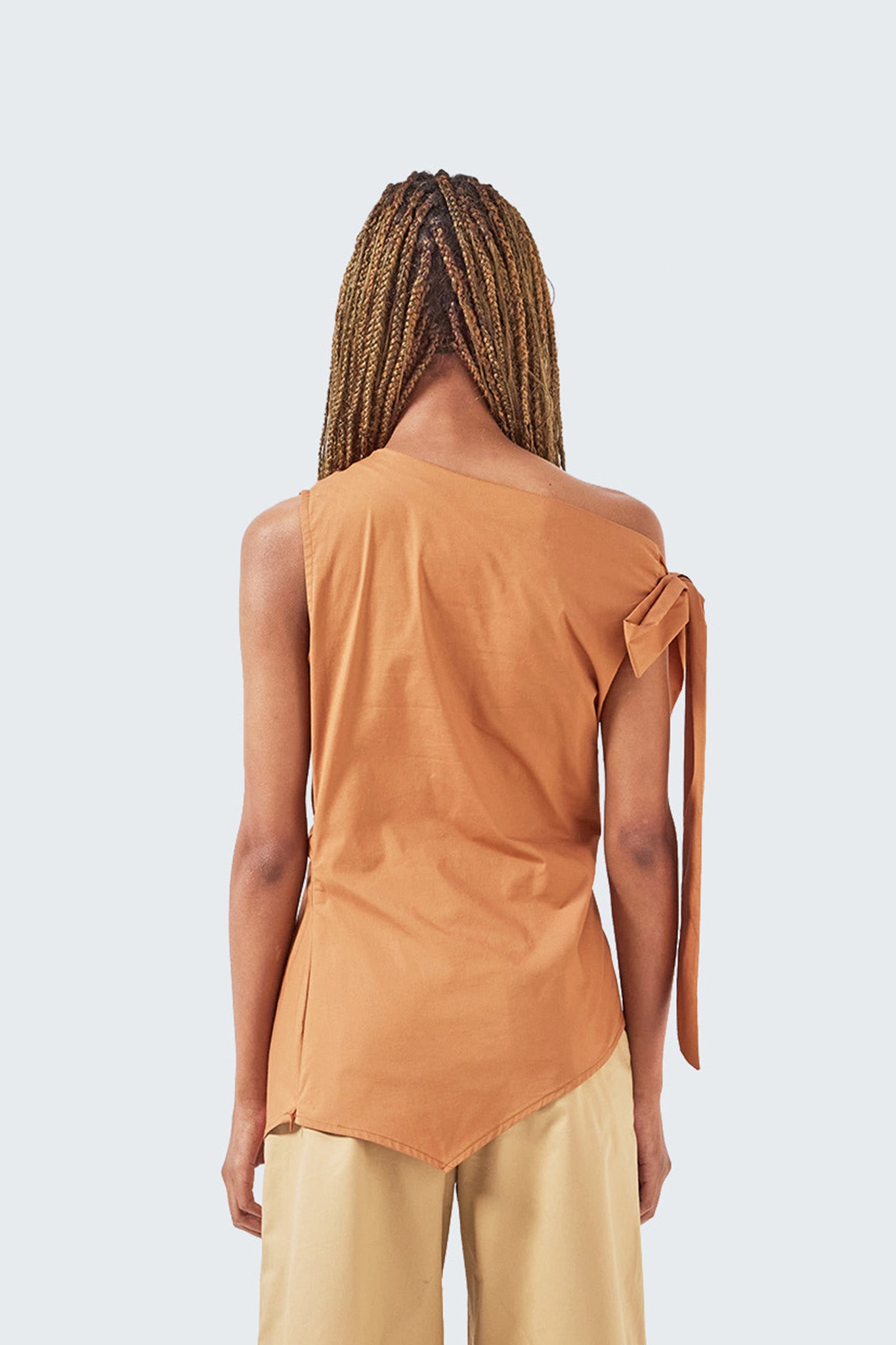Pambil One-Shoulder Knotted Top in Brick viewed from the back, featuring an asymmetric shoulder design and adjustable shoulder tie.