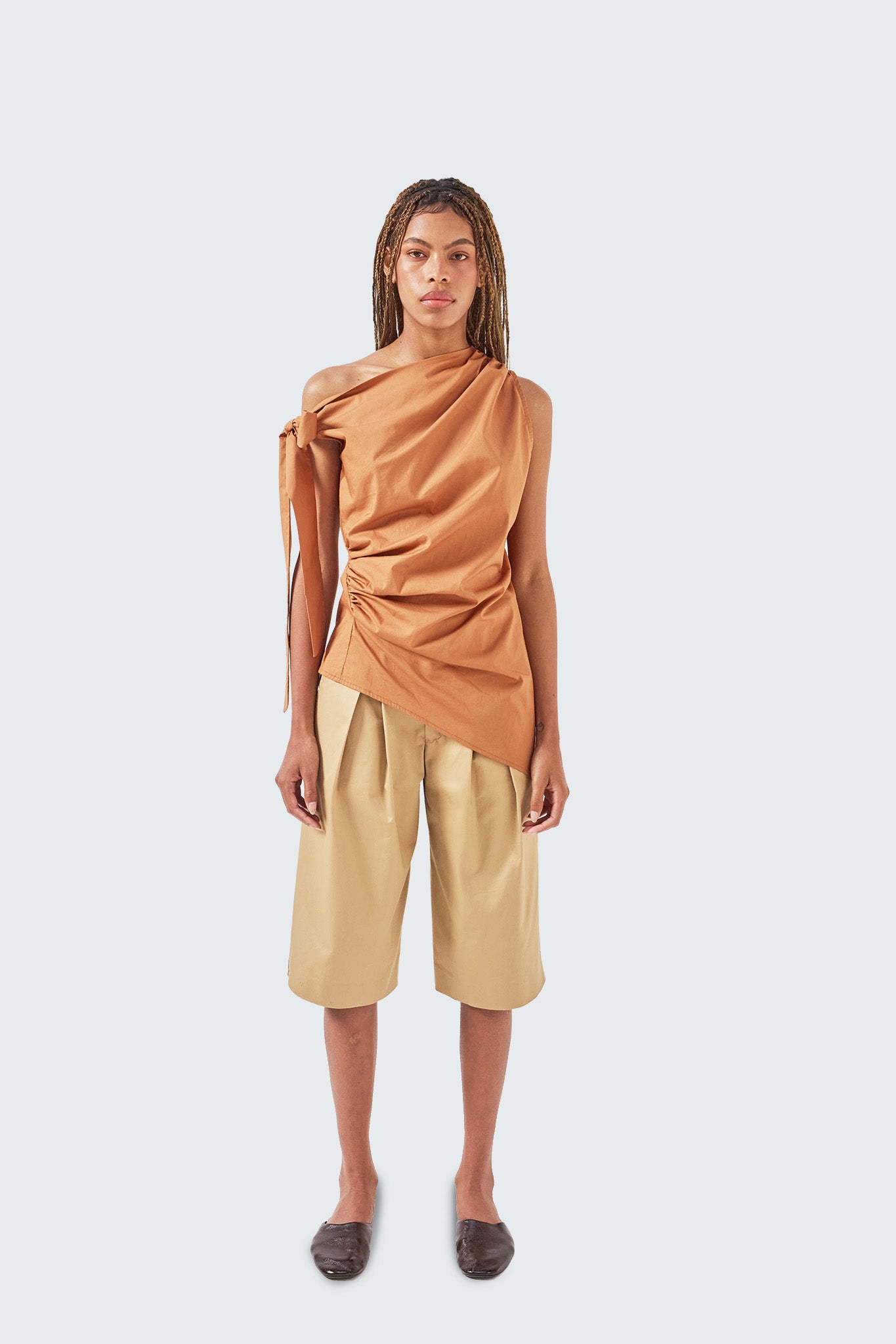 Front view of the Pambil One-Shoulder Knotted Top in Brick with draped bodice and adjustable shoulder tie.