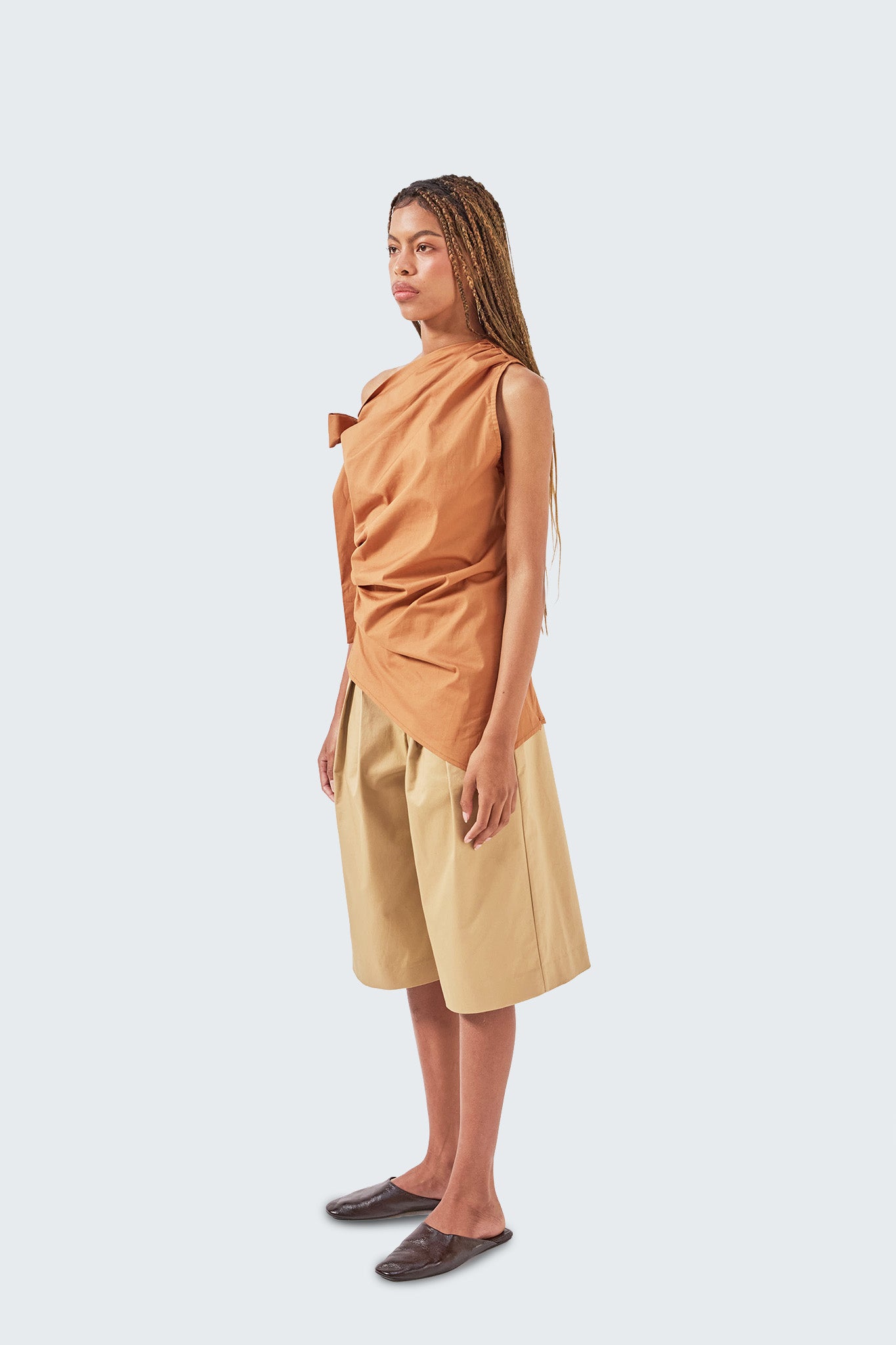 Side profile of the Pambil One-Shoulder Knotted Top showing sculptural draping and asymmetric hem.