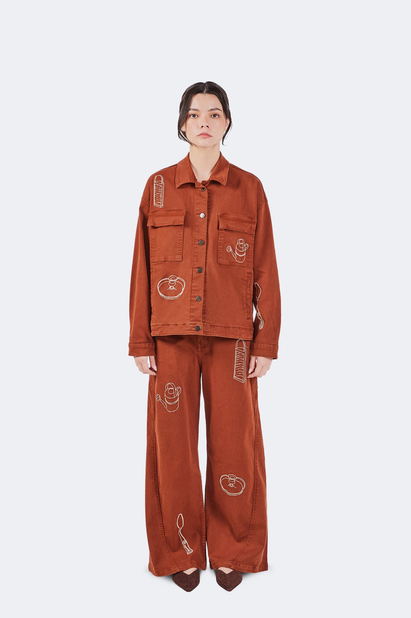 Front view of Payla Jeans in Brick featuring a relaxed wide-leg silhouette and embroidered artistic motifs.