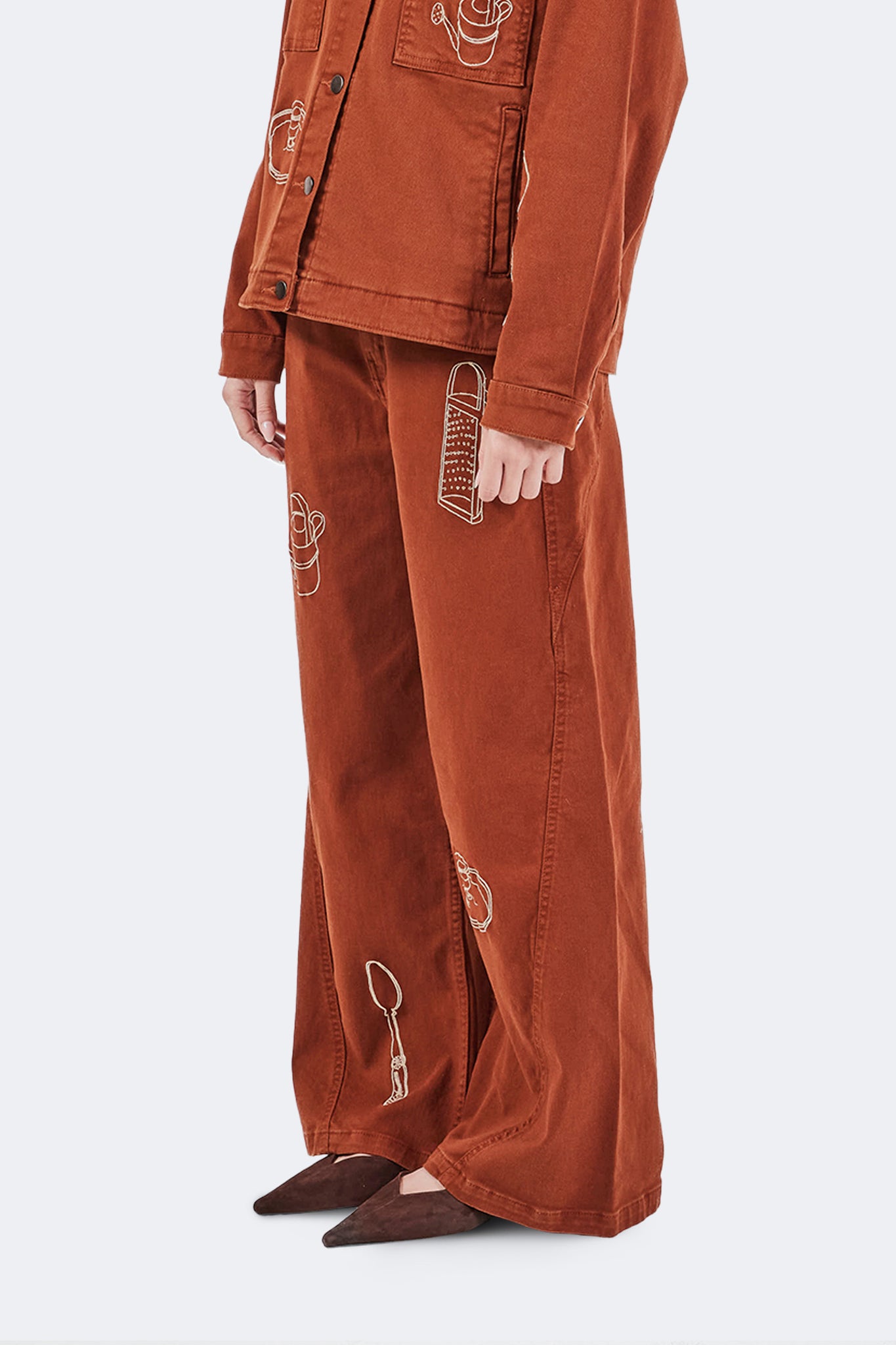 Side detail of Payla Jeans in Brick highlighting embroidered archive motifs and wide-leg denim construction.