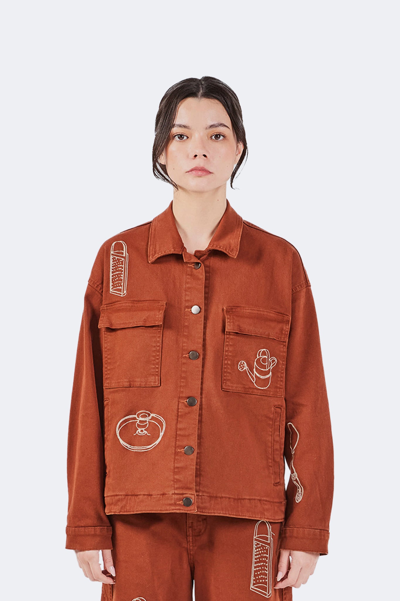 Payla Workman Jacket in Brick cotton denim featuring oversized patch pockets, front button closure, and archive-inspired embroidered motifs, shown with coordinating wide-leg trousers.