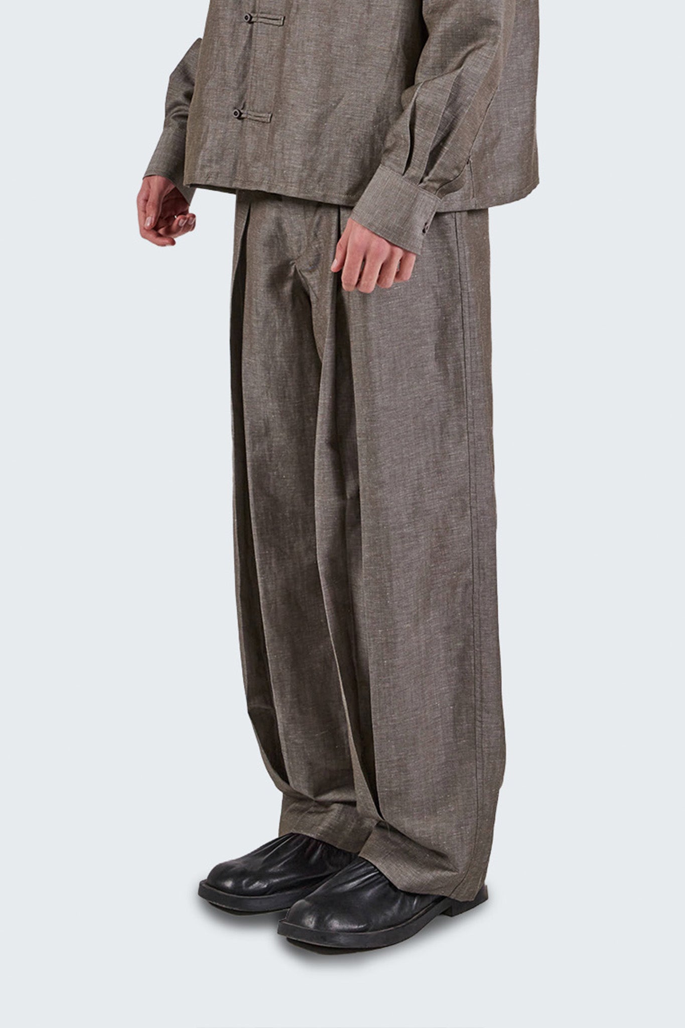 Close-up side view of Pita Double Pleated Trousers highlighting textured wool-linen fabric and fluid drape.