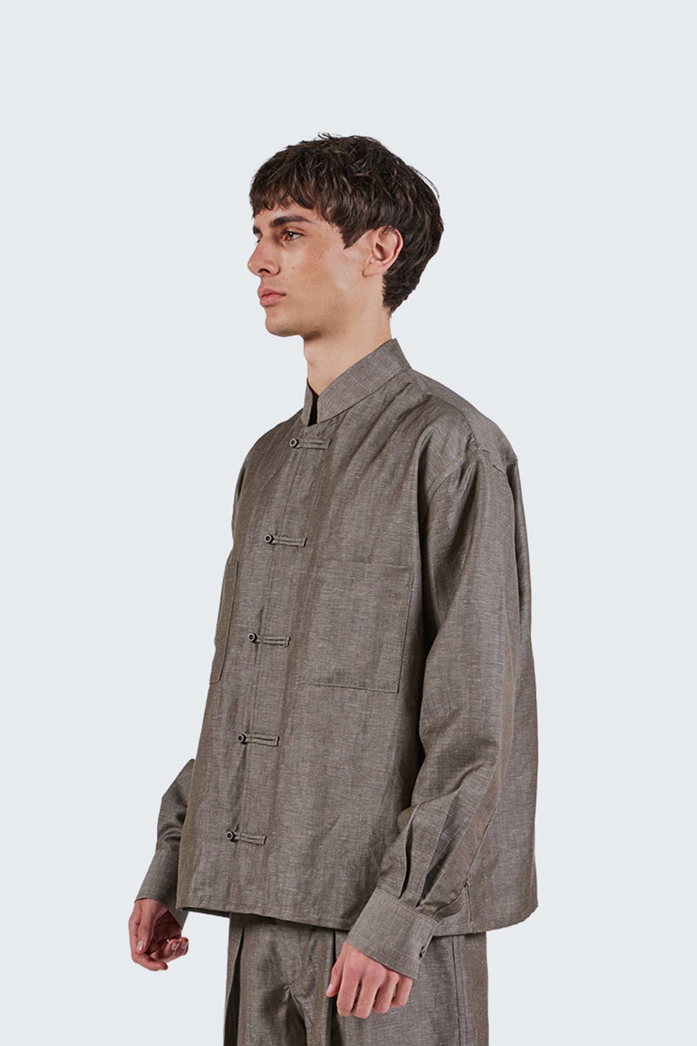 Close-up side view of the Pita Mao Collared Shirt showcasing traditional frog-button closures and textured grey fabric.