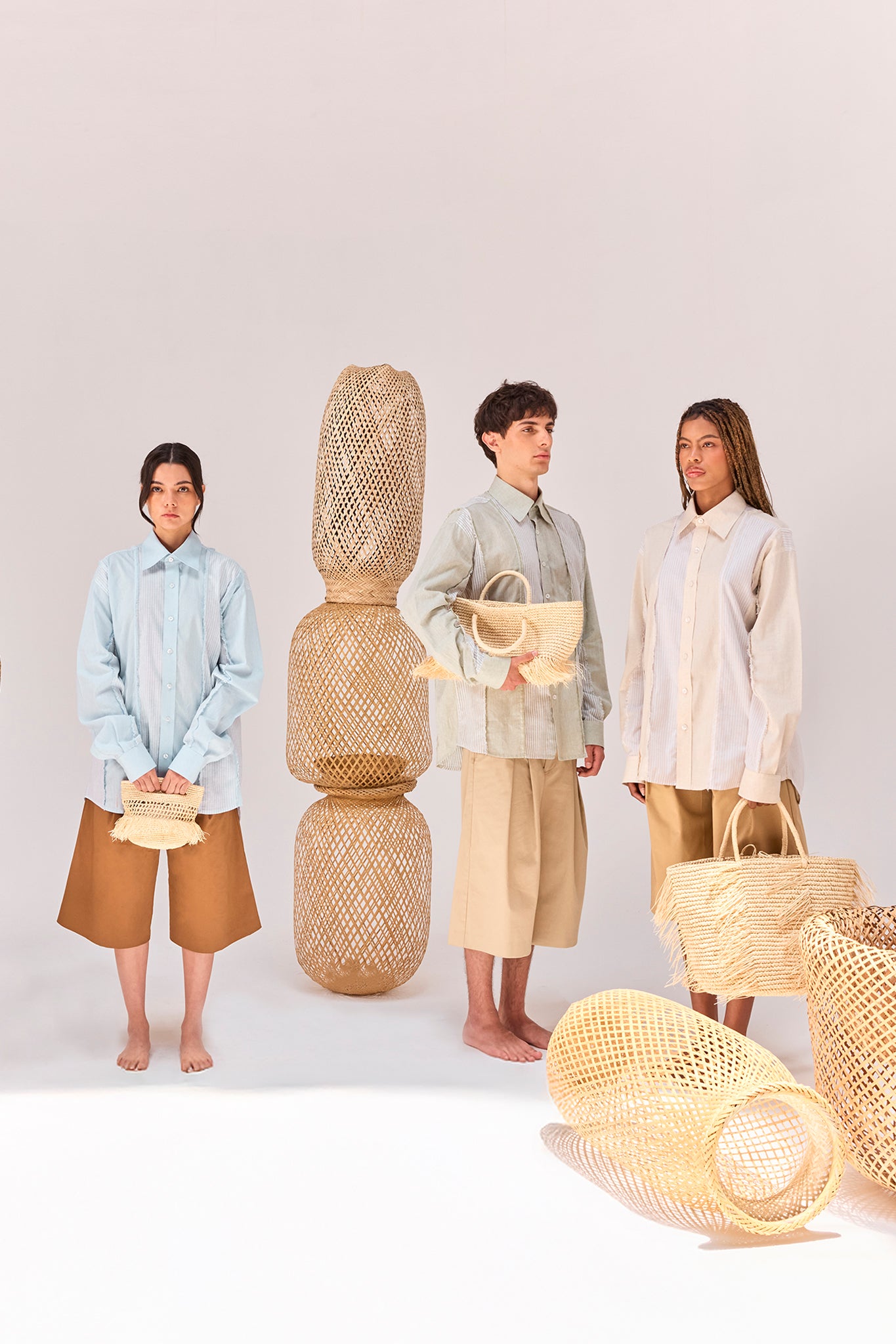 Editorial featuring the Salango Striped Shirt collection in Sky, Baby Moss, and Sand, styled with tailored shorts, woven artisanal bags, and handcrafted wicker sculptures.