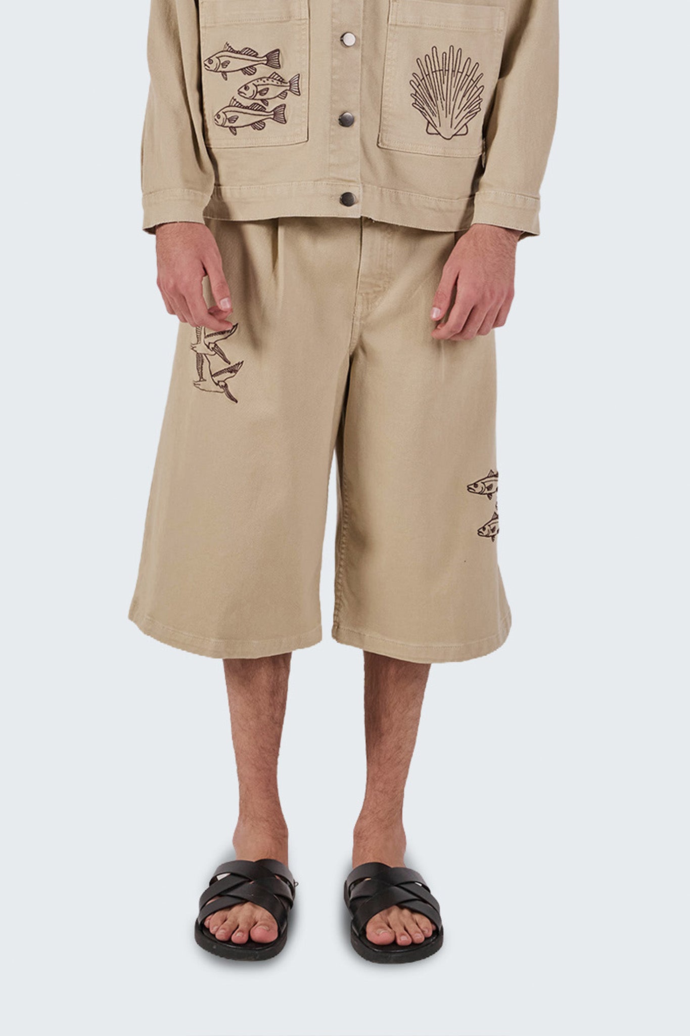 Detailed front view highlighting embroidered bird and fish motifs, cotton construction, and clean tailoring.