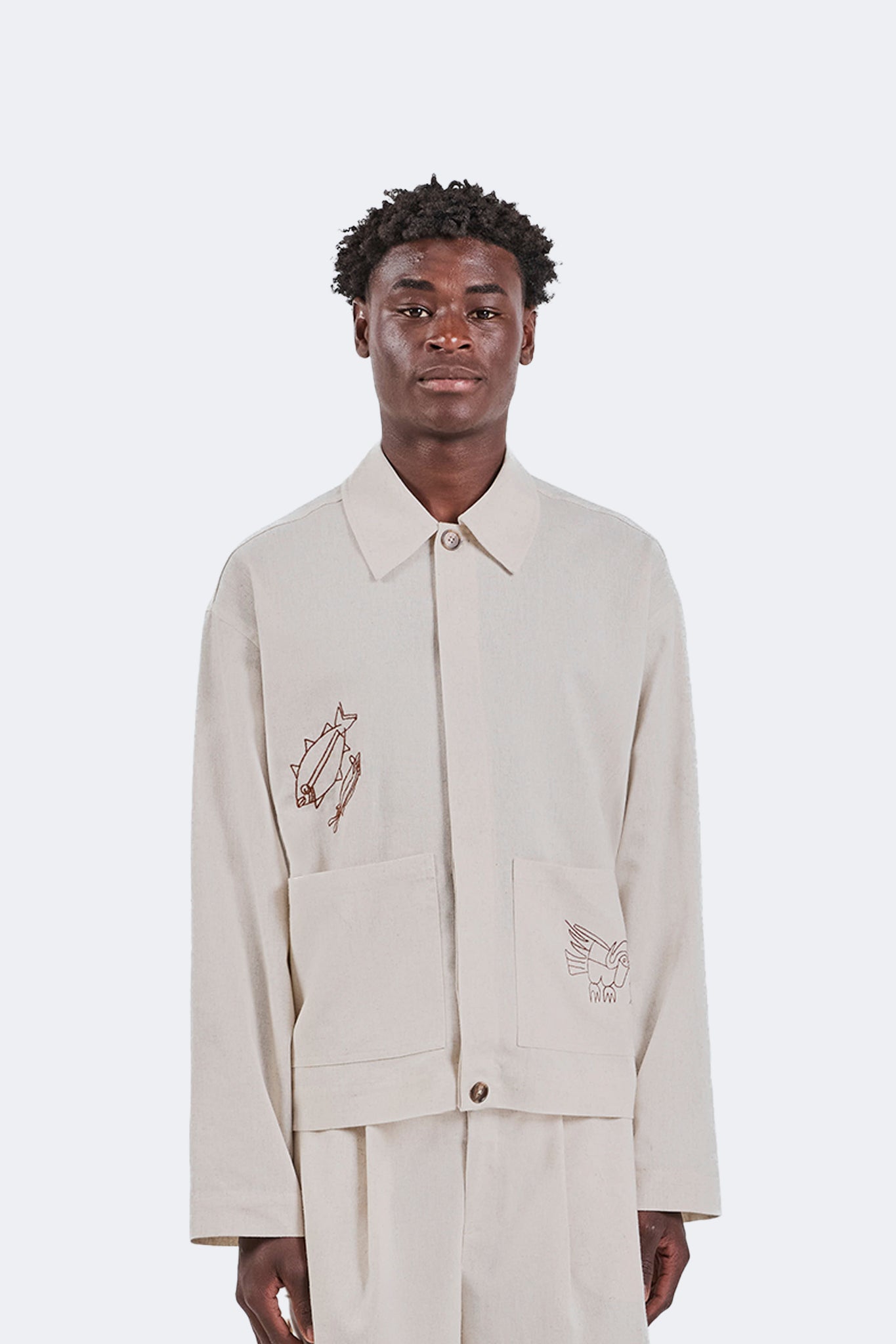 Front detail of the Salango Linen Utility Jacket in Off-White featuring embroidered coastal motifs, oversized patch pockets, button-front closure, and a relaxed utility silhouette.