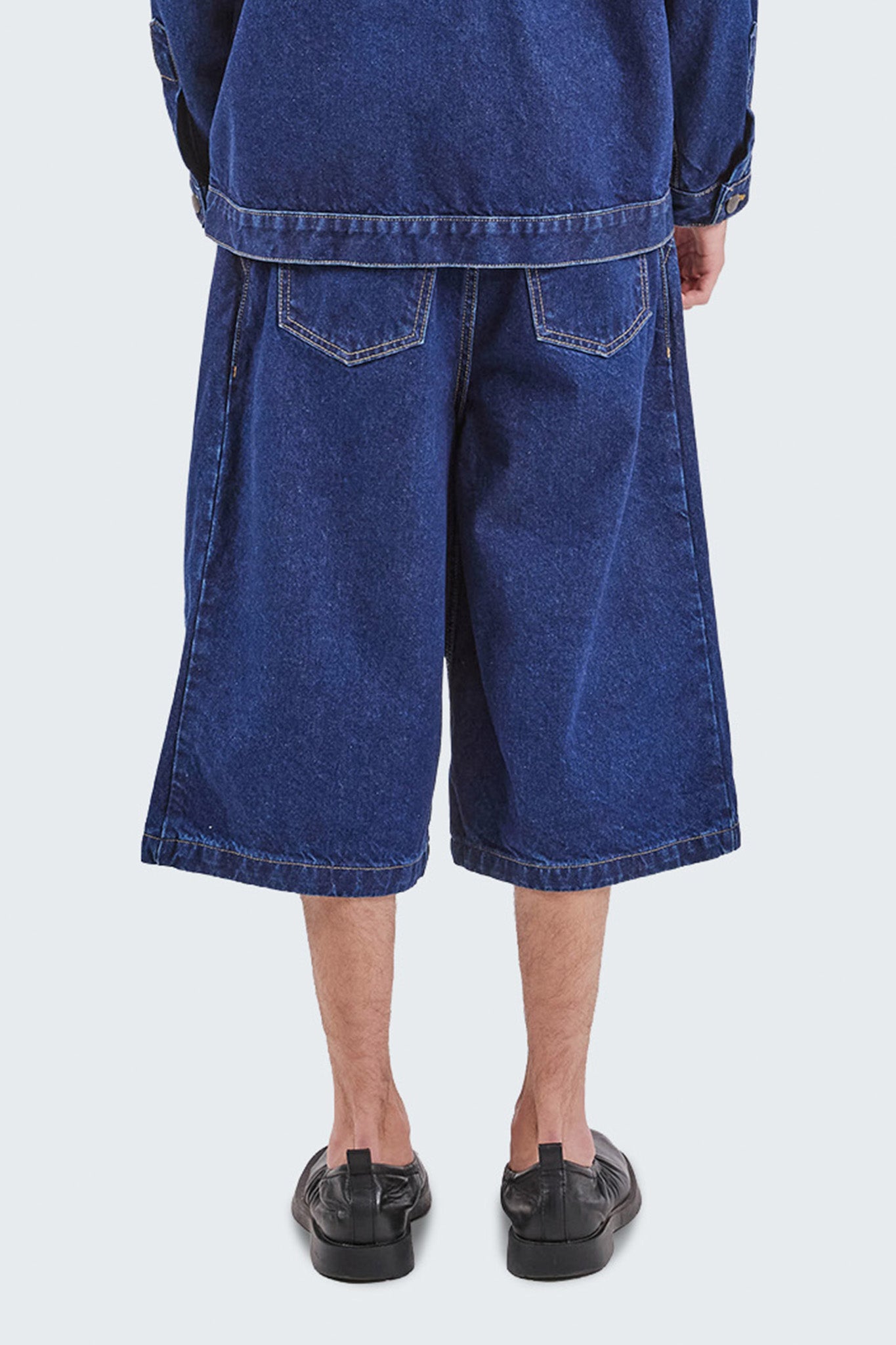 Back detail of the Salango Raw Denim Jorts showing rear patch pockets, contrast topstitching, and wide-leg denim construction.