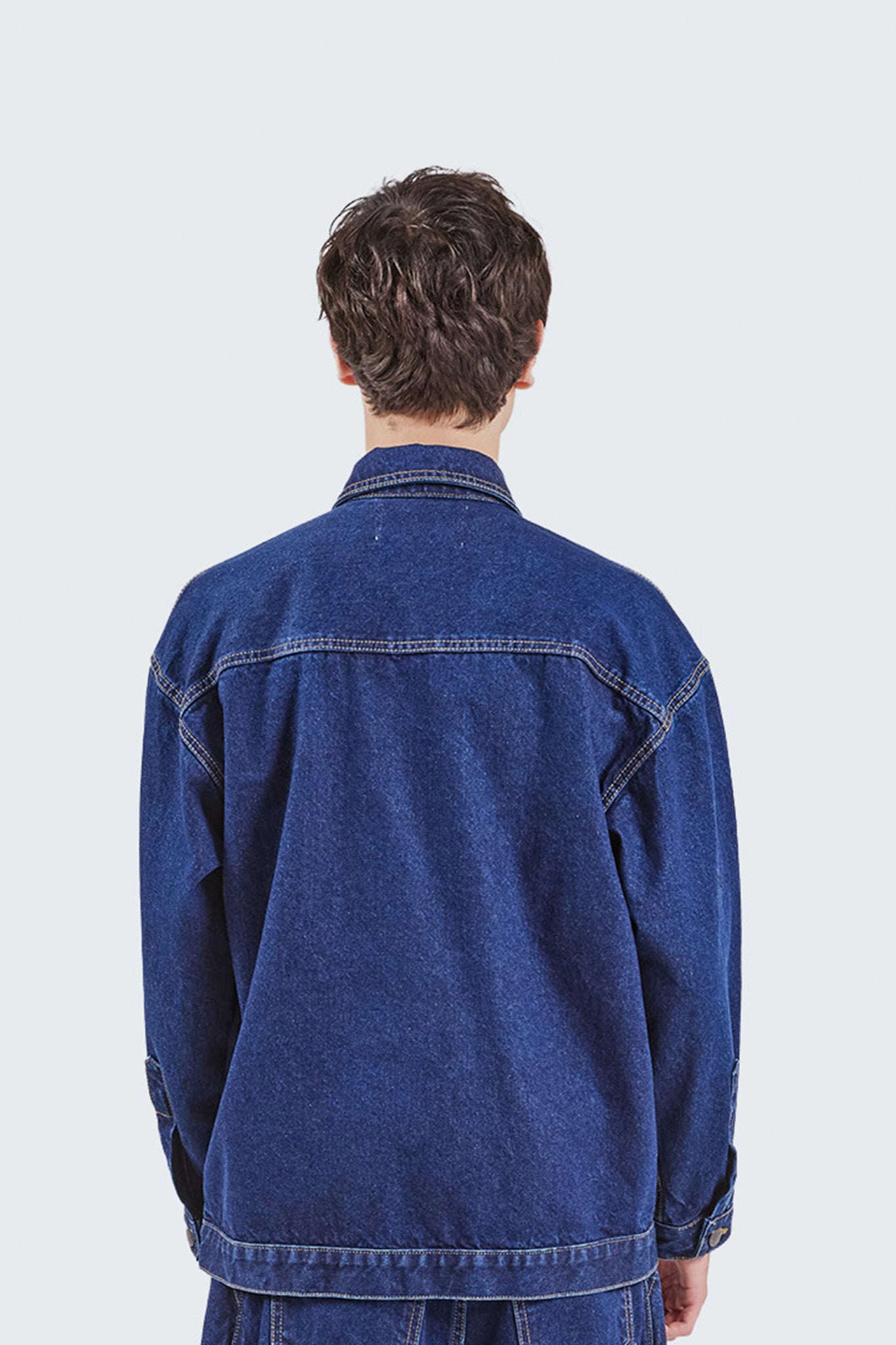 Back detail view of the Salango Raw Denim Workman Jacket featuring clean indigo denim construction, contrast topstitching, dropped shoulders, and a relaxed workwear silhouette.