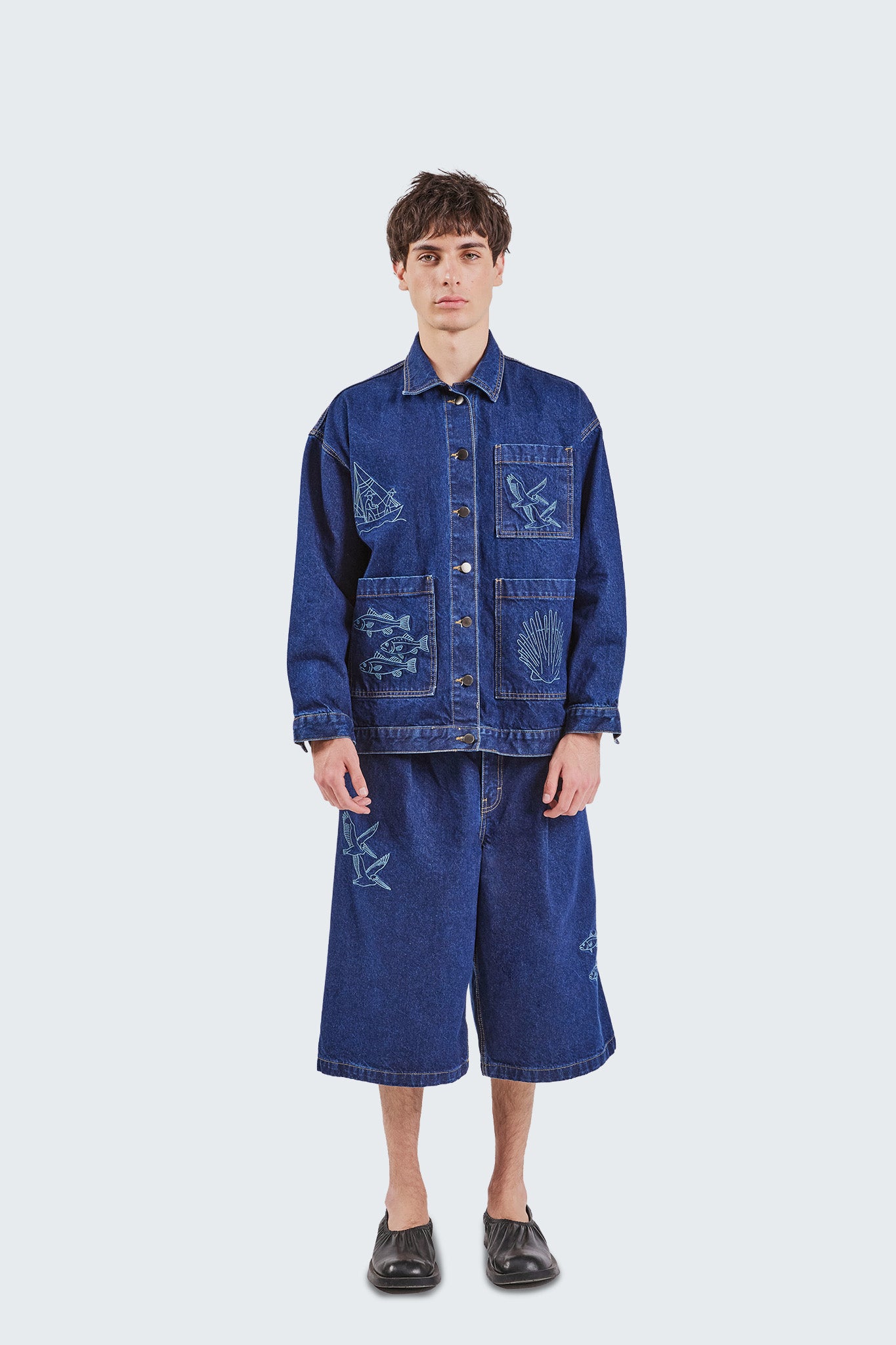 Front view of the Salango Raw Denim Workman Jacket showcasing oversized patch pockets, embroidered coastal artwork, and button-front closure.
