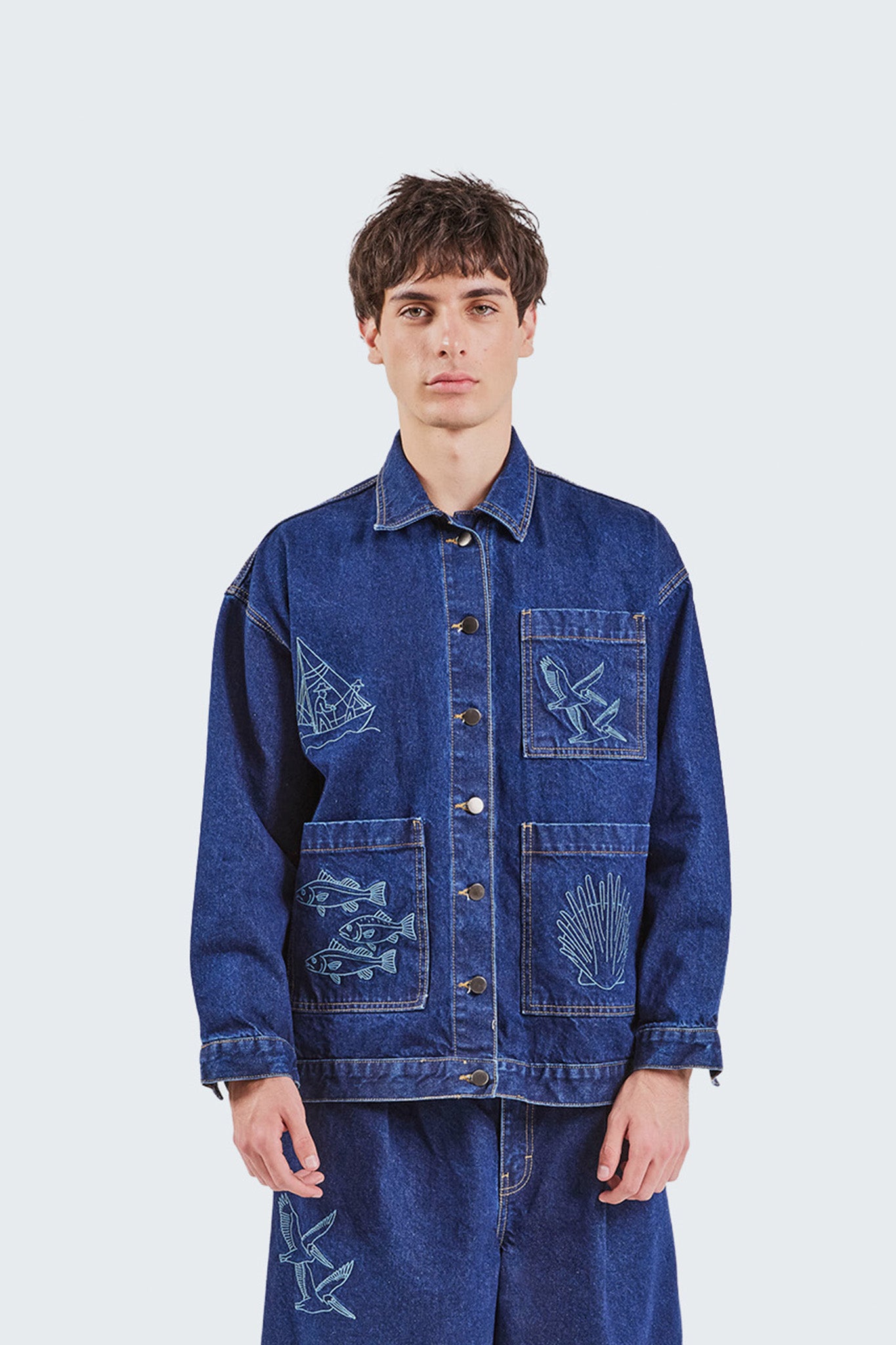 Front detail of the Salango Raw Denim Workman Jacket highlighting embroidered marine-inspired artwork, structured denim construction, contrast stitching, and utility pocket design.