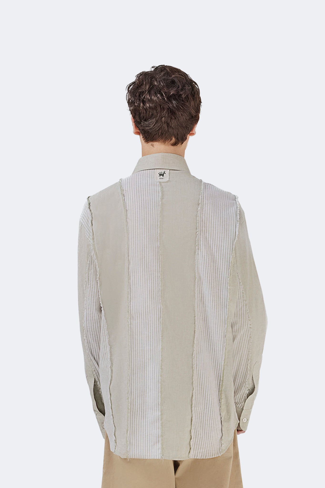 Close-up back view of the Salango Striped Shirt in Baby Moss highlighting the signature label, contrasting striped panels, and exposed raw-edge seams.