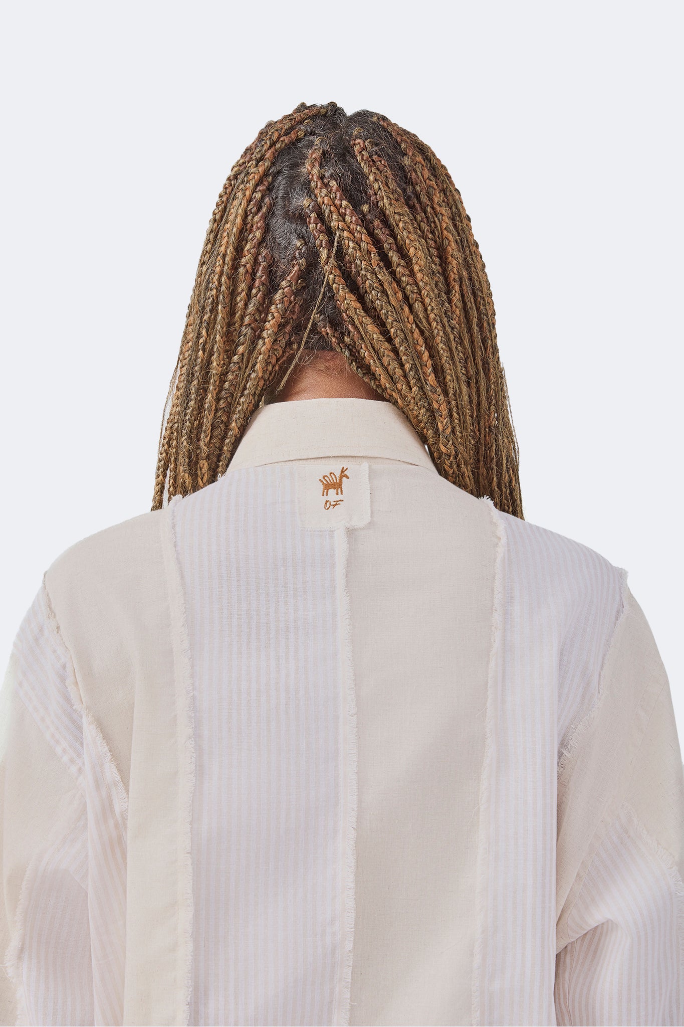 Back detail of the Salango Striped Shirt in Sand showcasing tonal striped panels, exposed raw-edge seams, signature Olga Fisch label, and classic point collar.