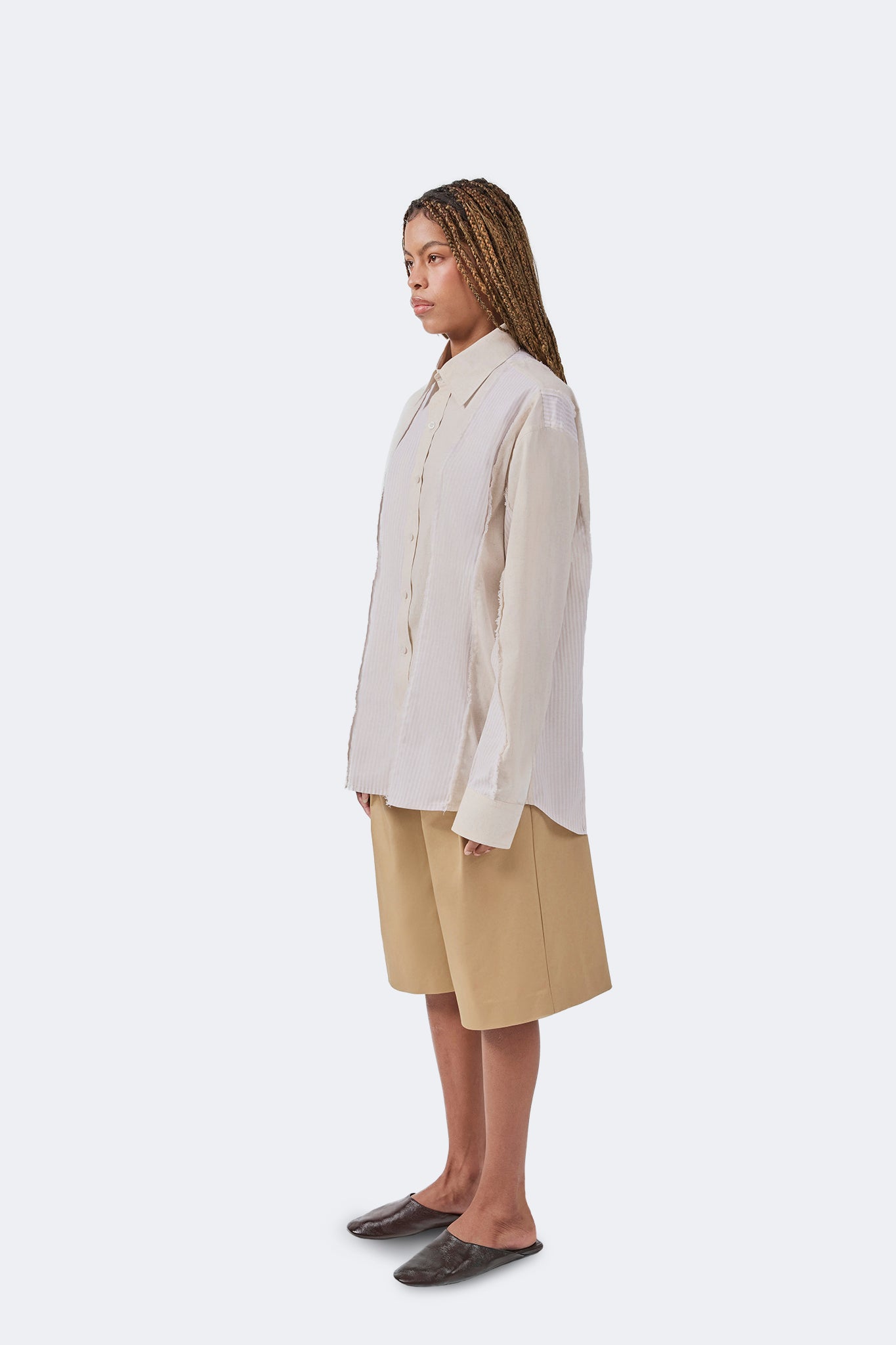 Side profile of the Salango Striped Shirt in Sand highlighting its relaxed silhouette, dropped shoulders, exposed raw-edge seams, and lightweight cotton construction.