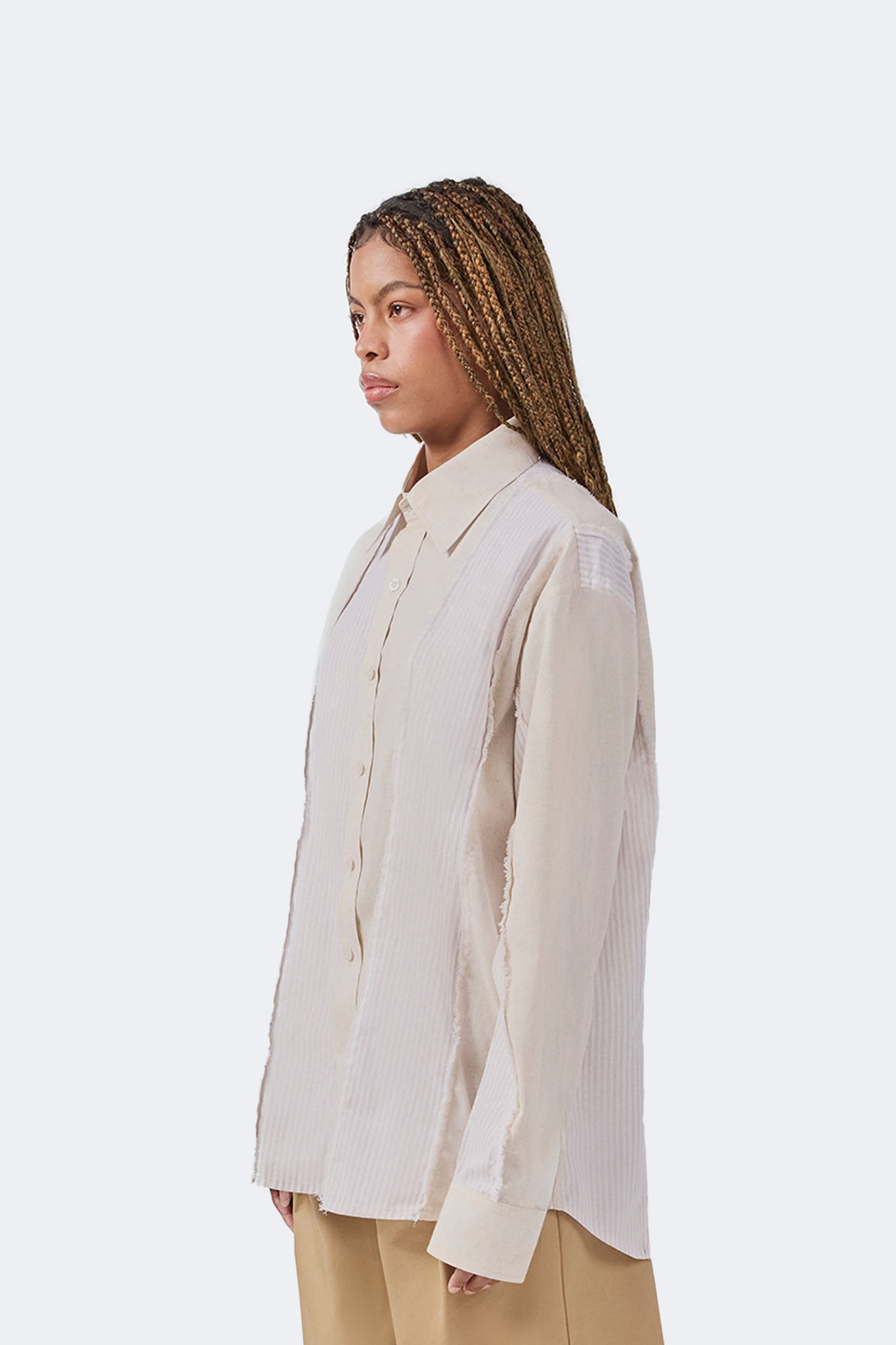 Side detail of the Salango Striped Shirt in Sand showcasing the relaxed silhouette, dropped shoulders, tonal striped panel construction, exposed raw-edge seams, and curved hem.