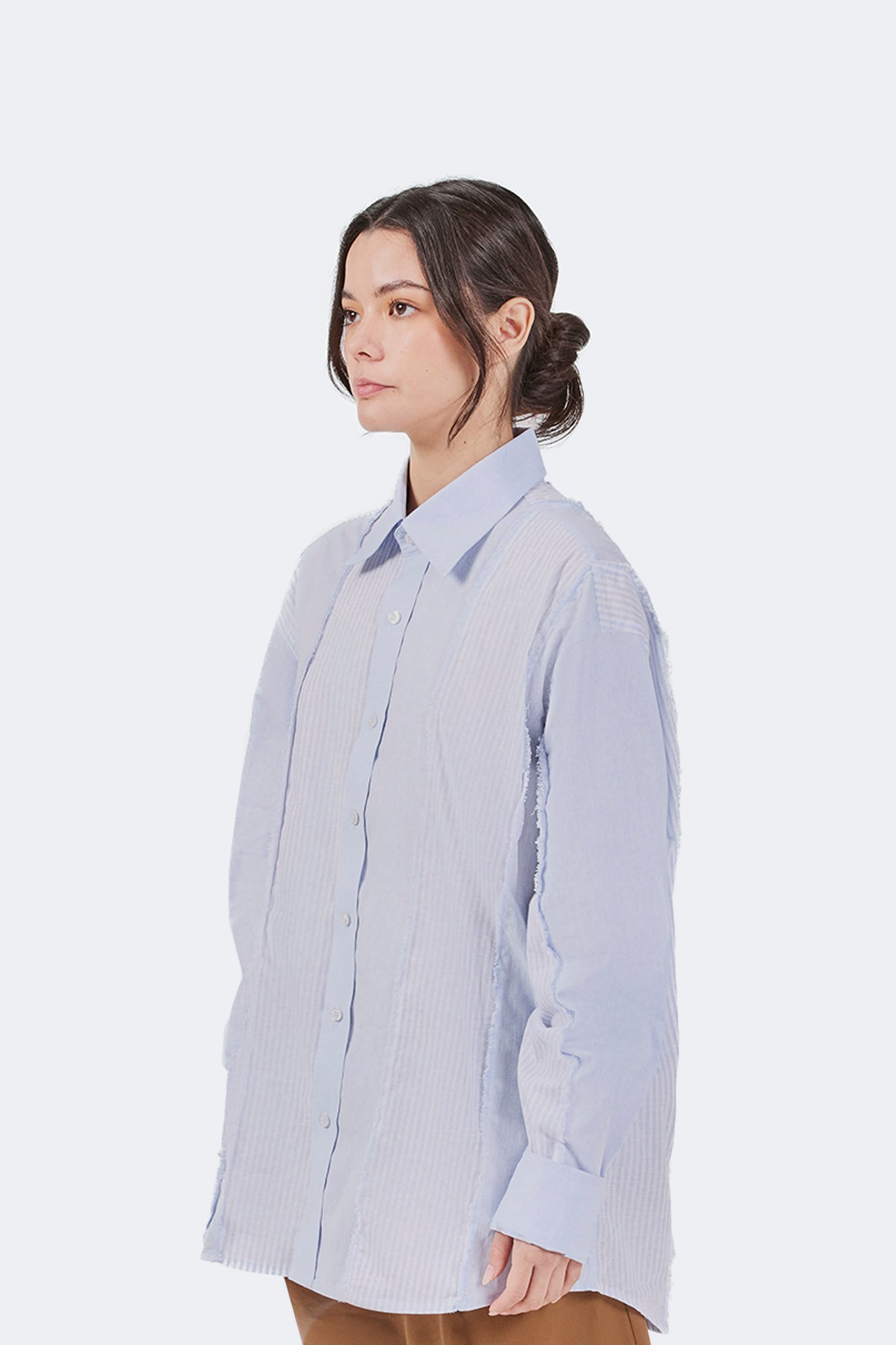 Side detail of the Salango Striped Shirt in Sky highlighting the relaxed silhouette, dropped shoulders, tonal striped panel construction, exposed raw-edge seams, and curved hem.