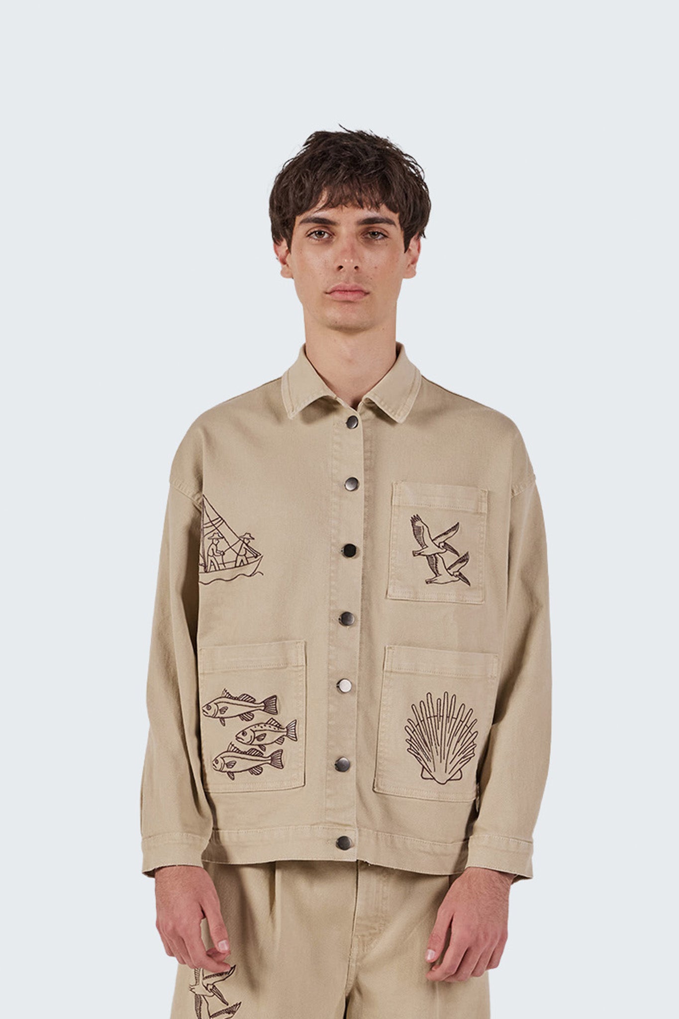 Close-up of the Salango Workman Jacket showcasing embroidered seabirds, shell motifs, and utility pocket construction.
