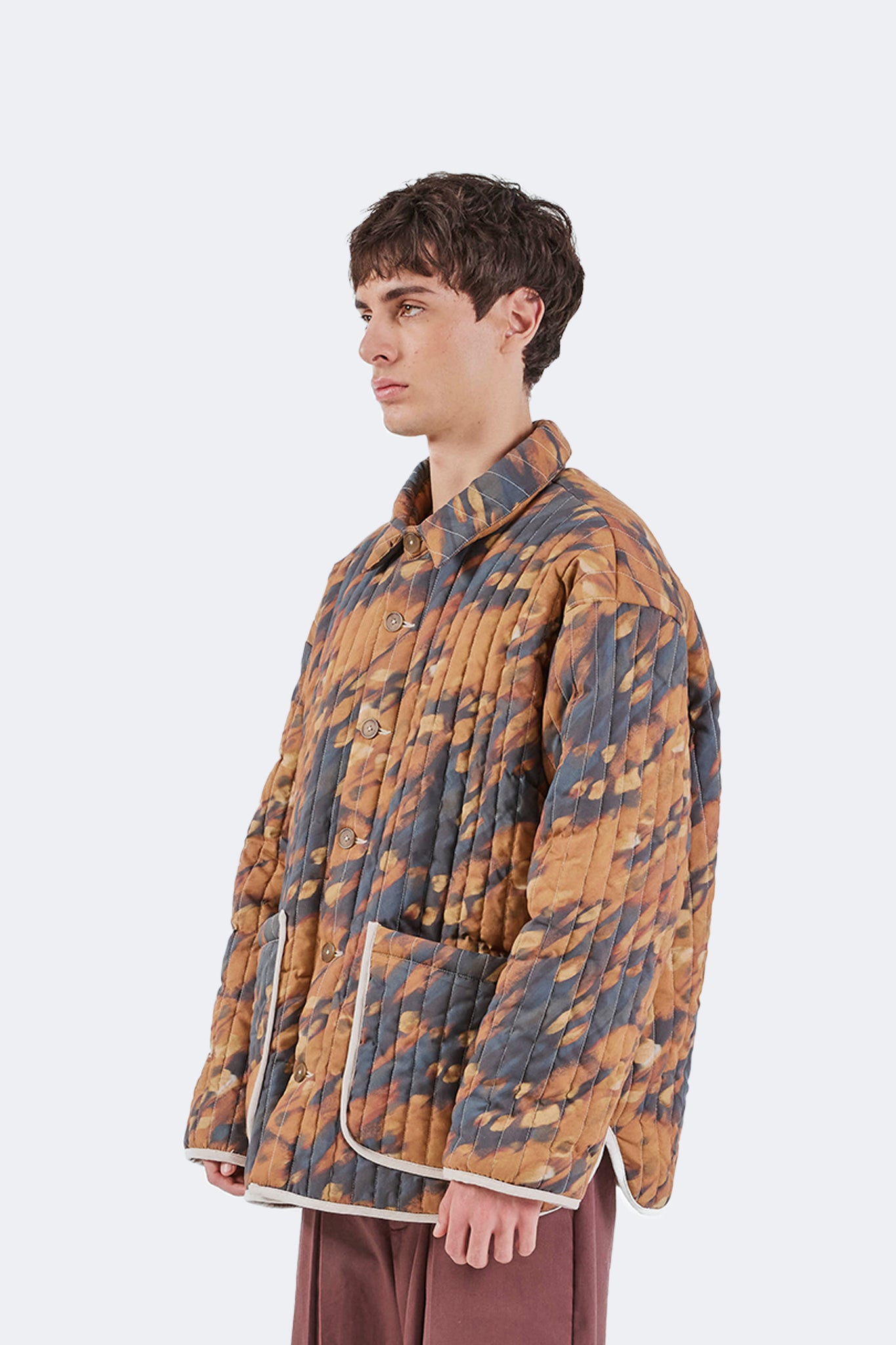 Side detail of the Same Quilted Jacket highlighting the relaxed silhouette, vertical quilting, contrast binding, and oversized patch pockets.